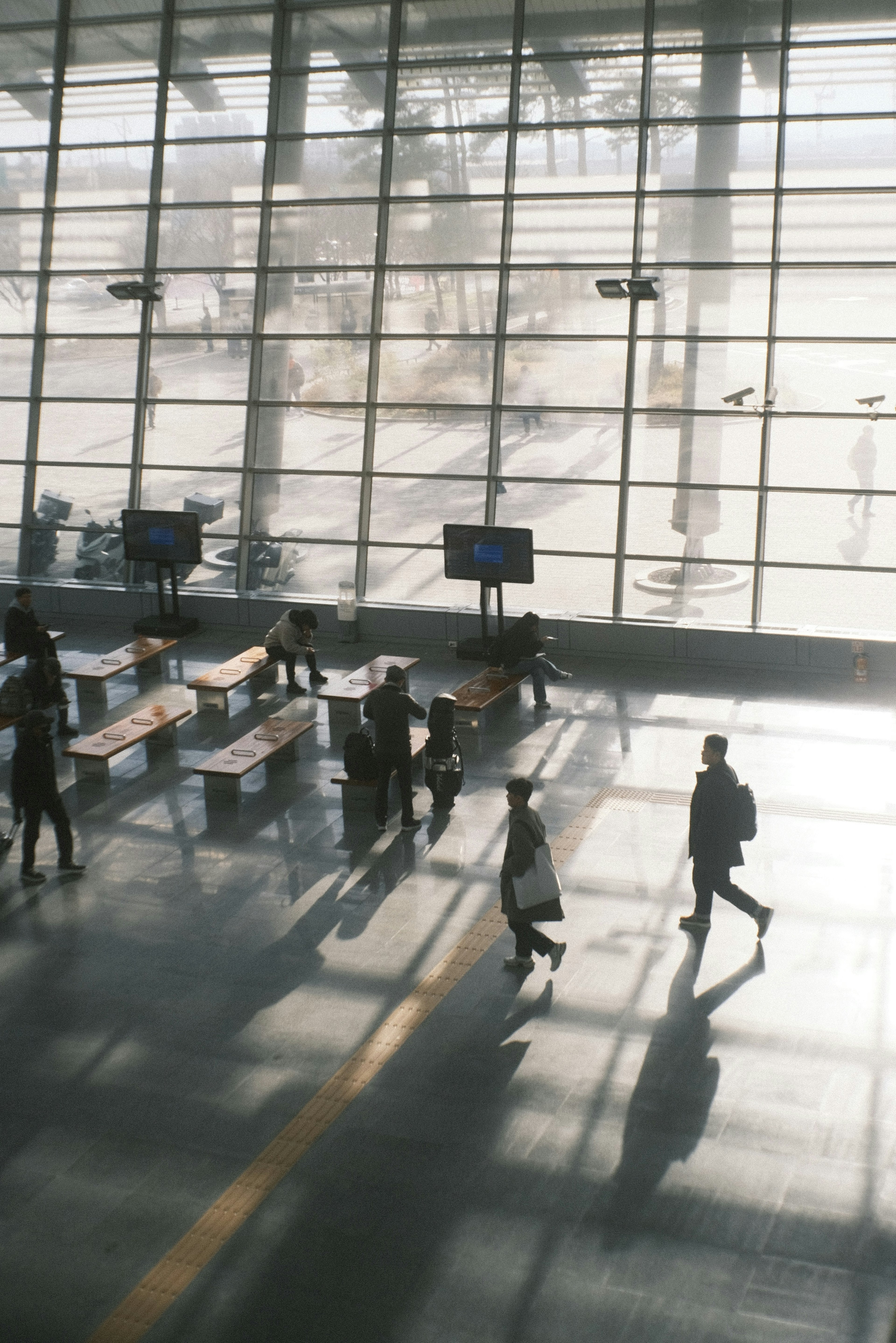 Menschen gehen in einem geräumigen Flughafen-Terminal mit großen Fenstern