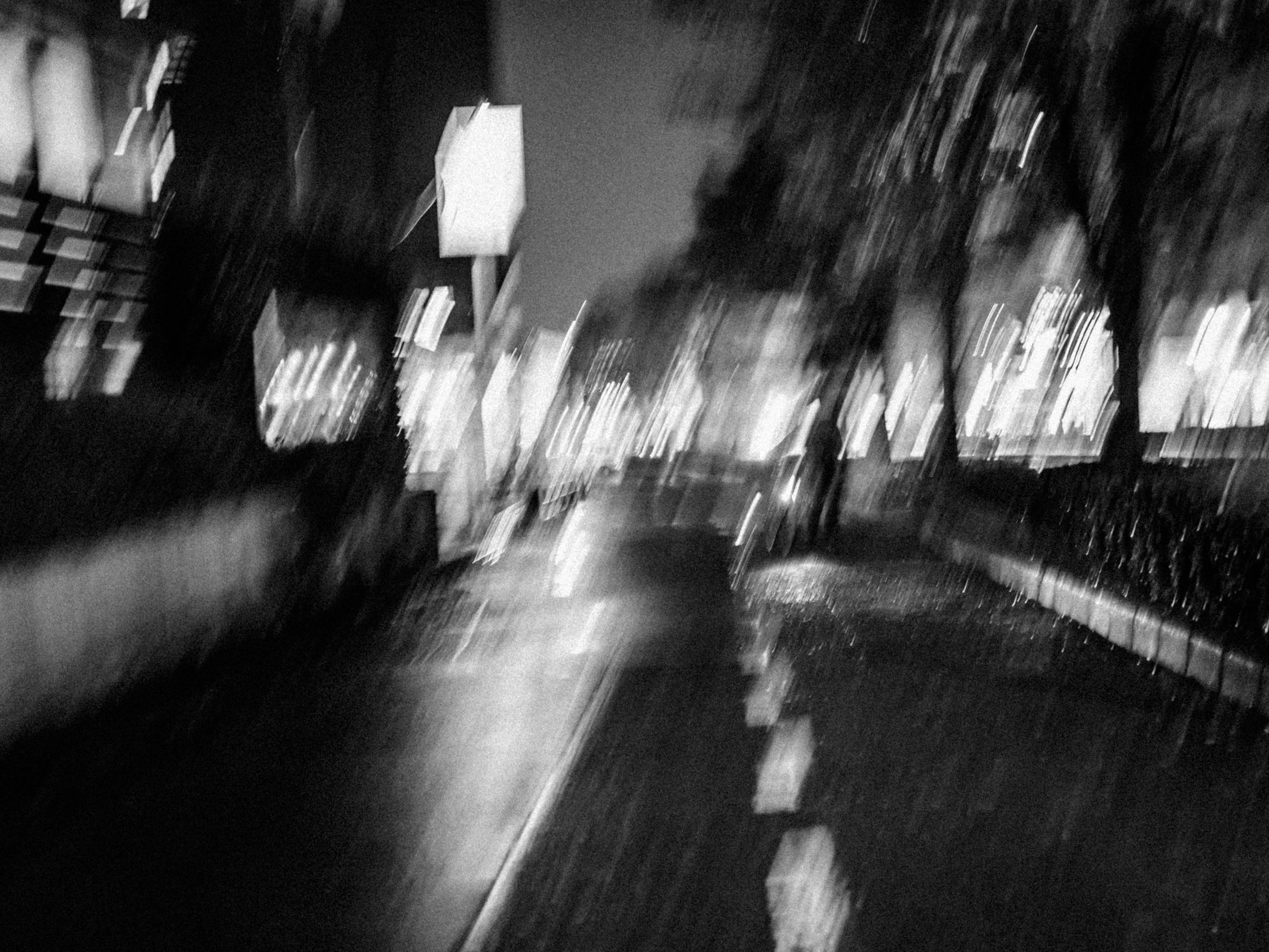 Blurred night cityscape featuring a monochrome road and street lights