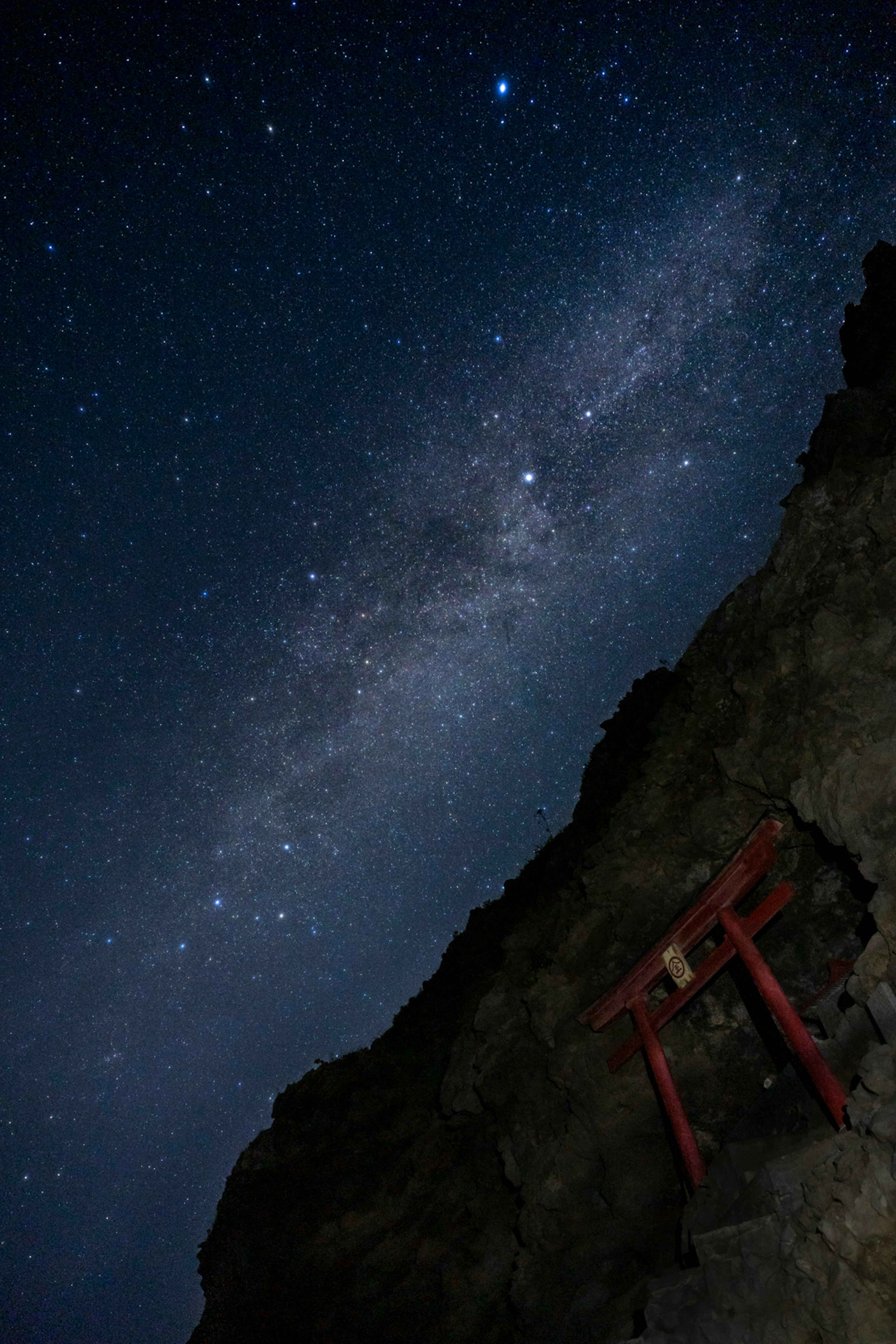 Paisaje nocturno con cielo estrellado y una puerta torii roja