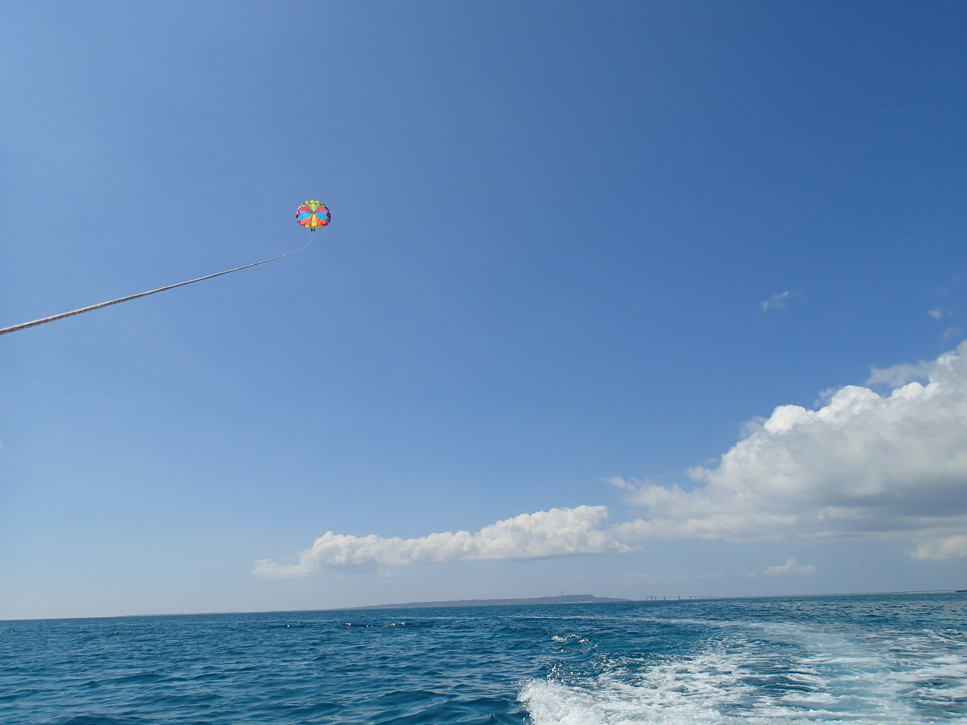 青い海と空の下でパラセーリングを楽しむ様子