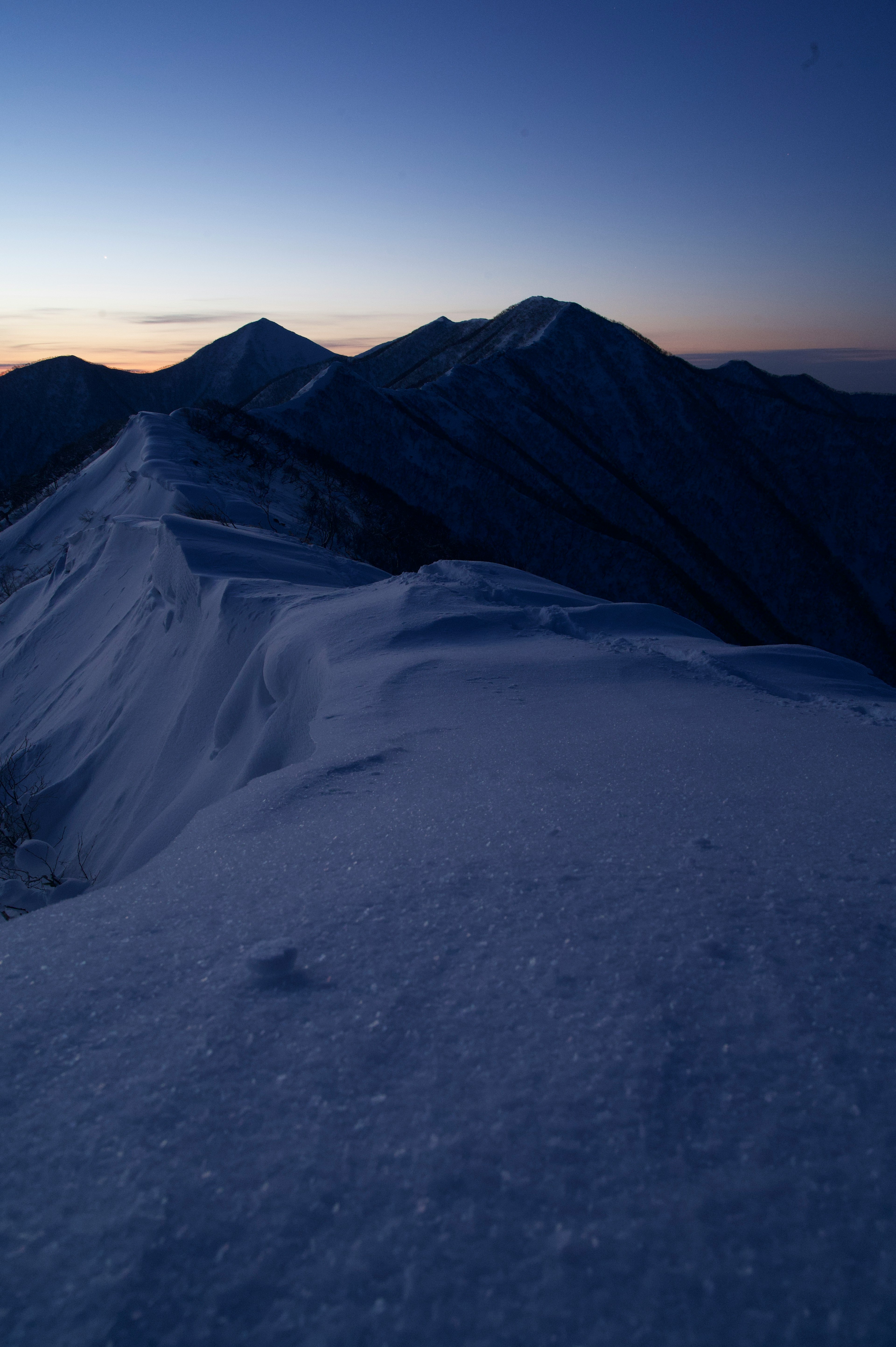 Snow-covered mountain ridge illuminated by twilight