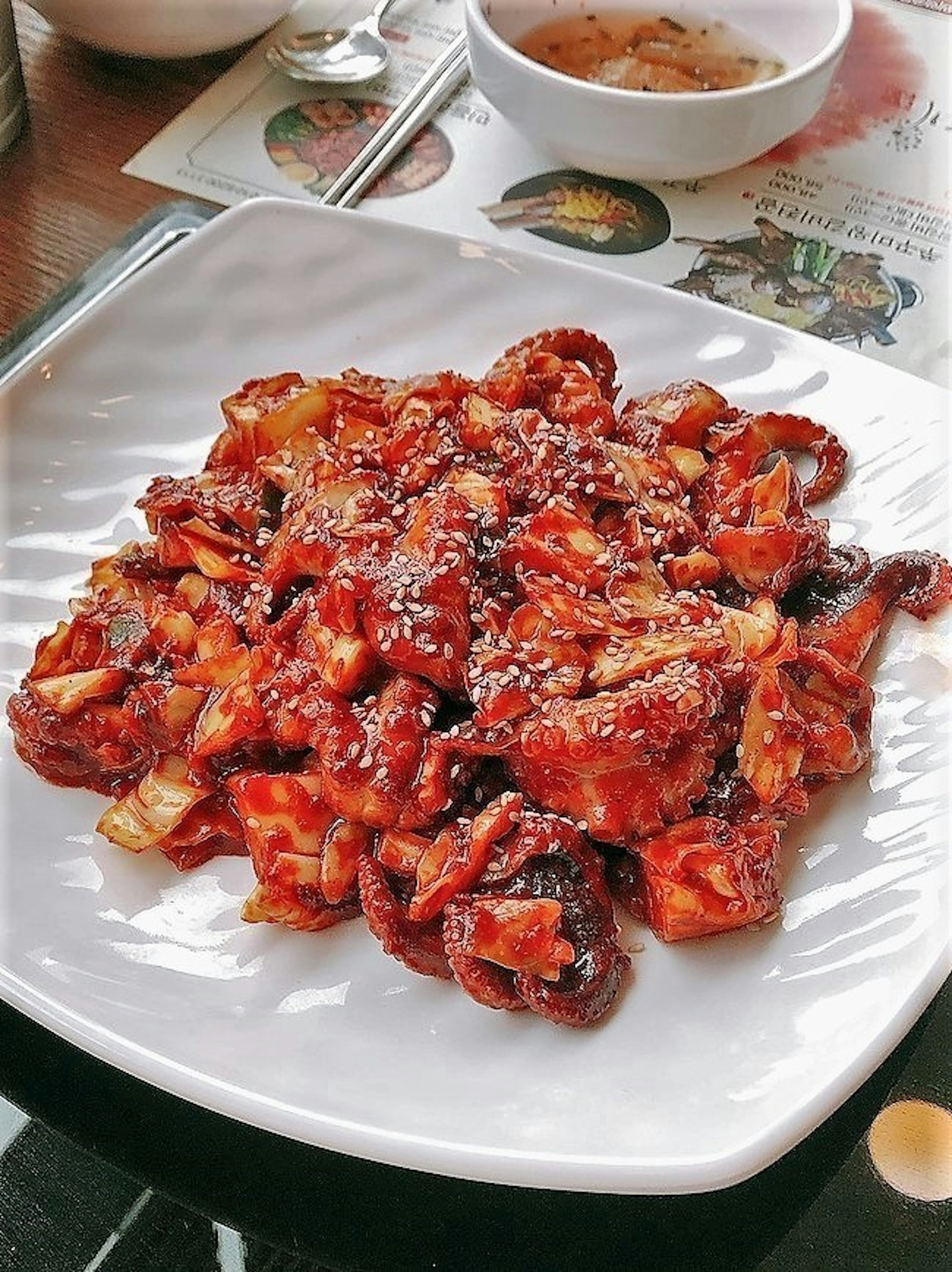 Dish of squid mixed in a sweet and spicy sauce topped with sesame seeds