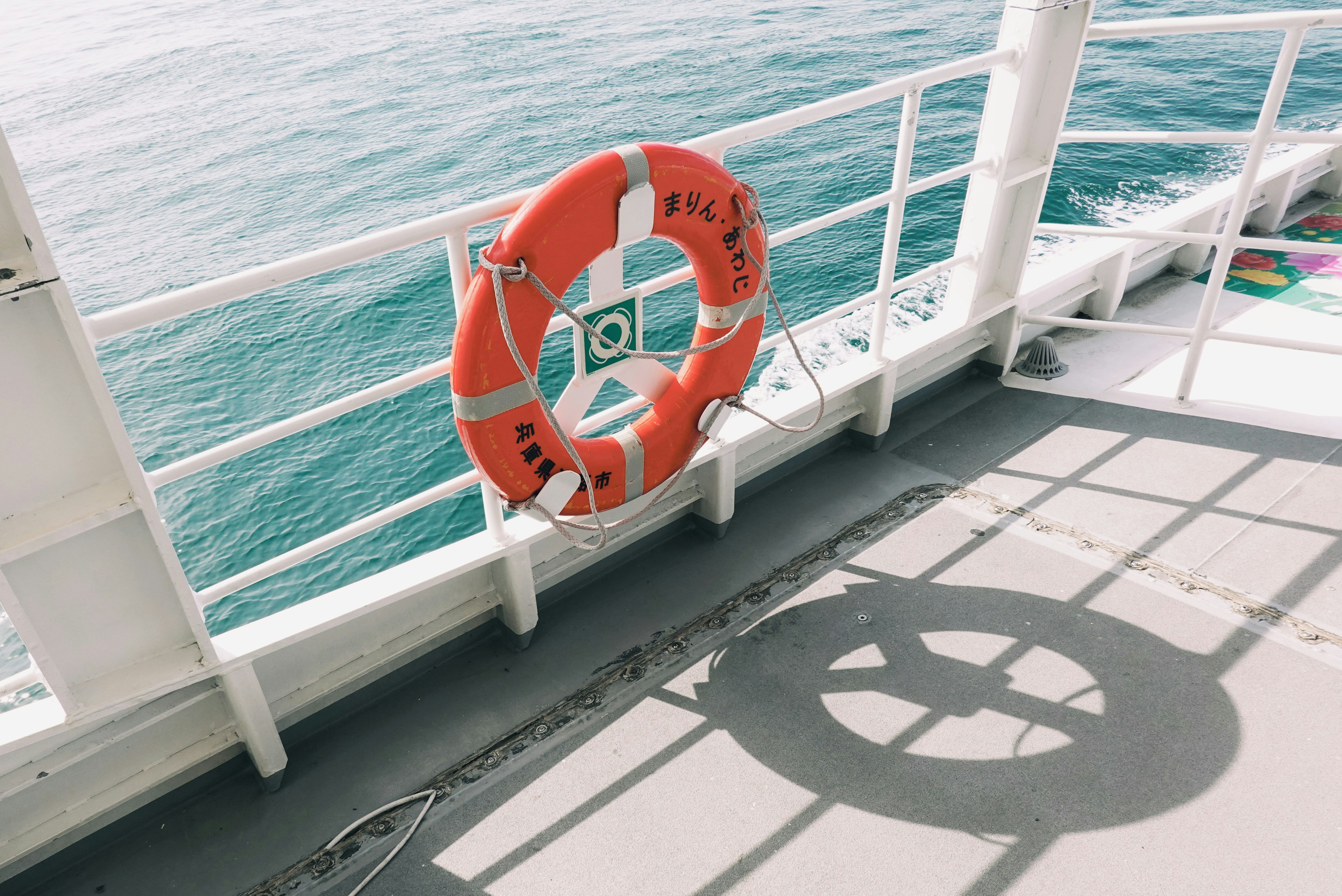 Bouée de sauvetage orange sur le pont d'un bateau avec son ombre