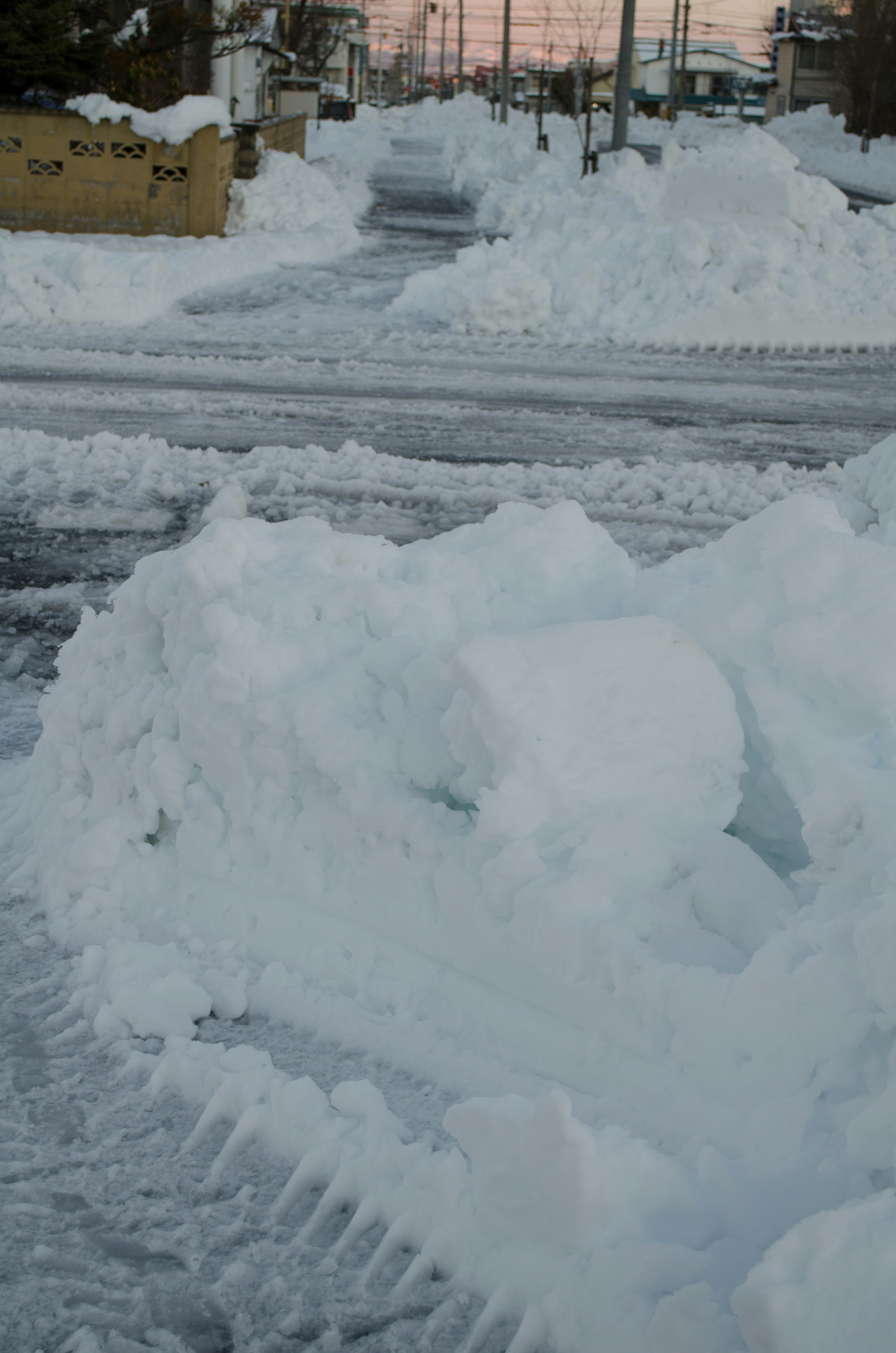 Snow-covered road with snow piles and tire tracks