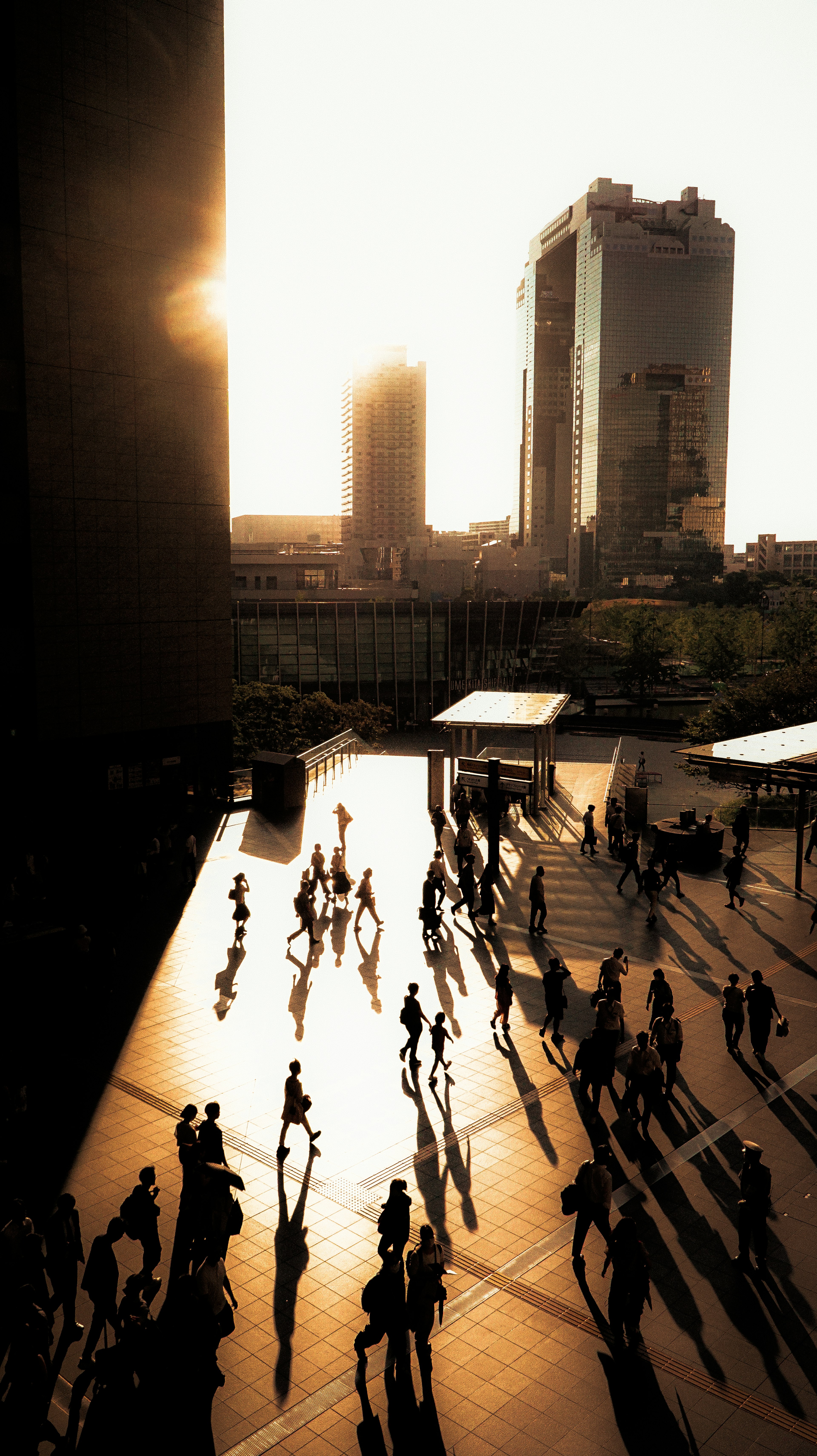 Urban scene with people walking against a sunset backdrop