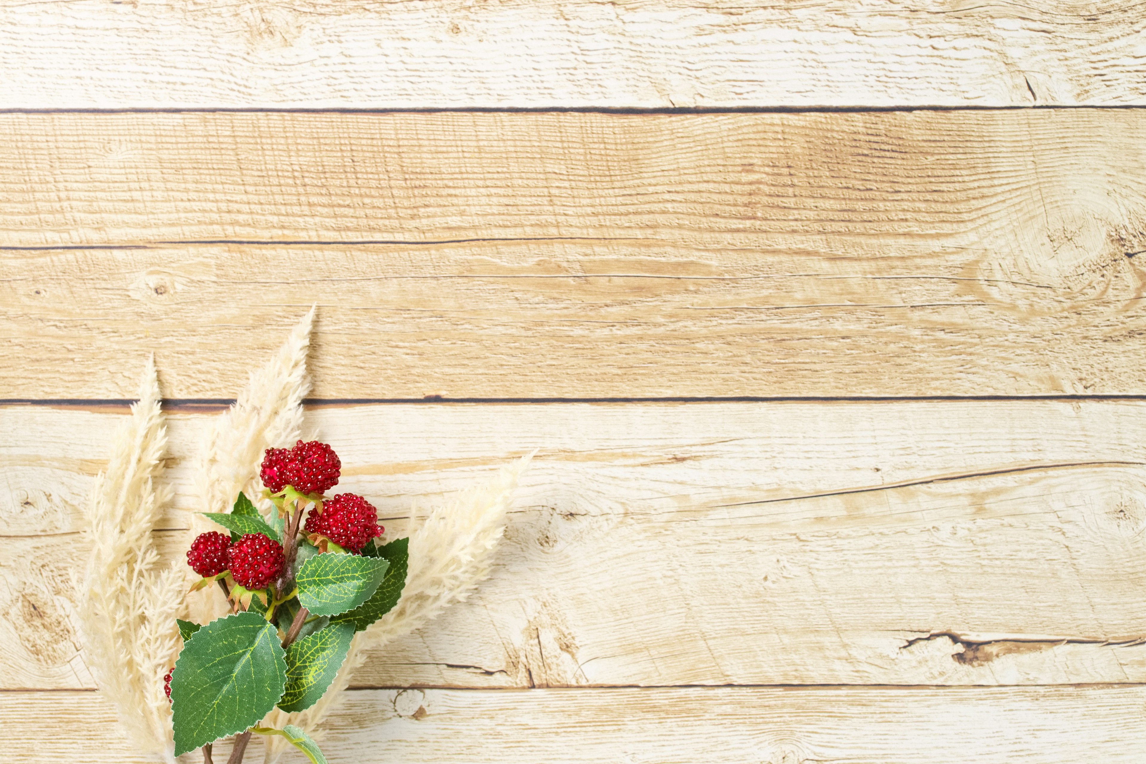 Red flowers and grass arrangement on a wooden background