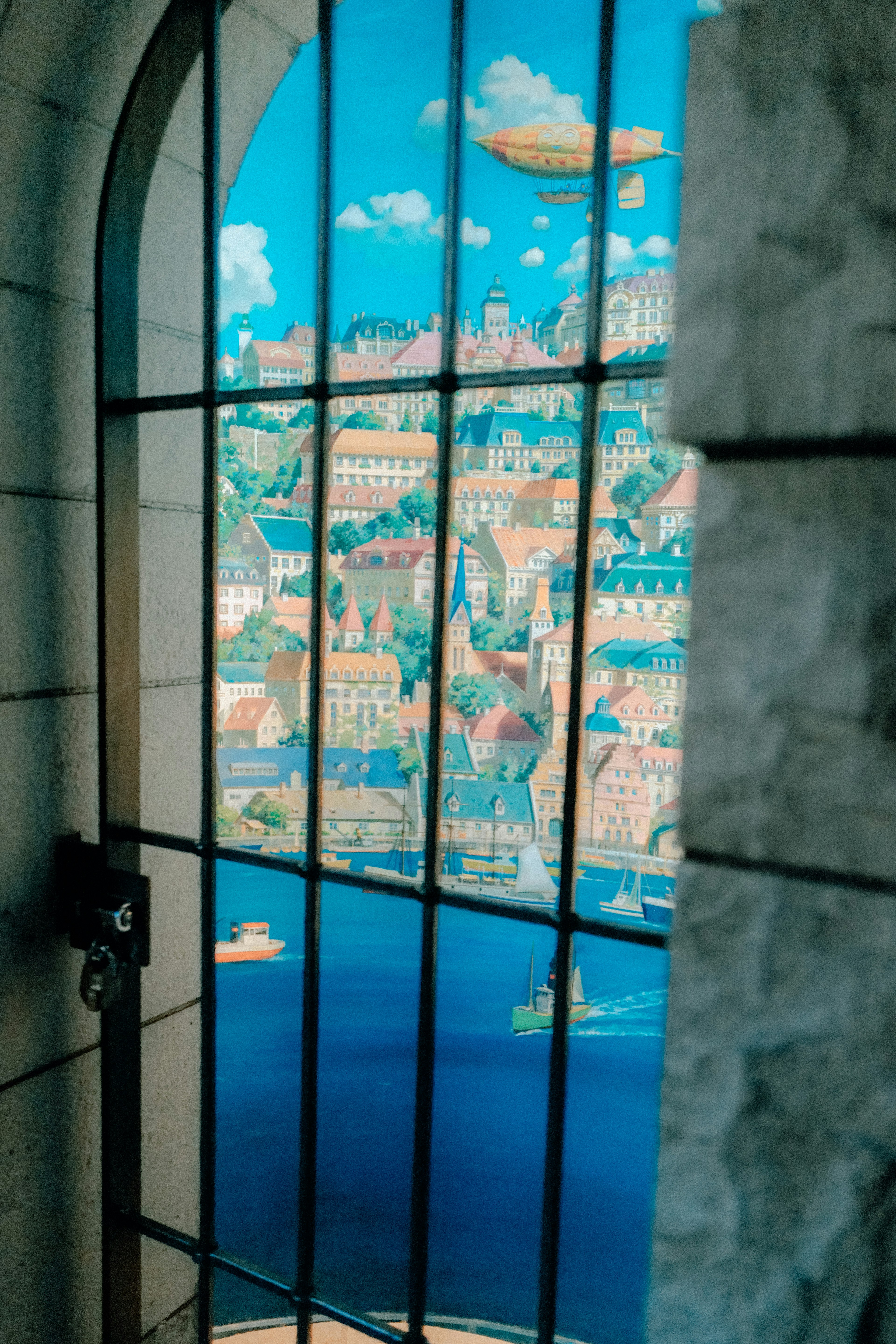 View through a window showing airships in the blue sky over a colorful city