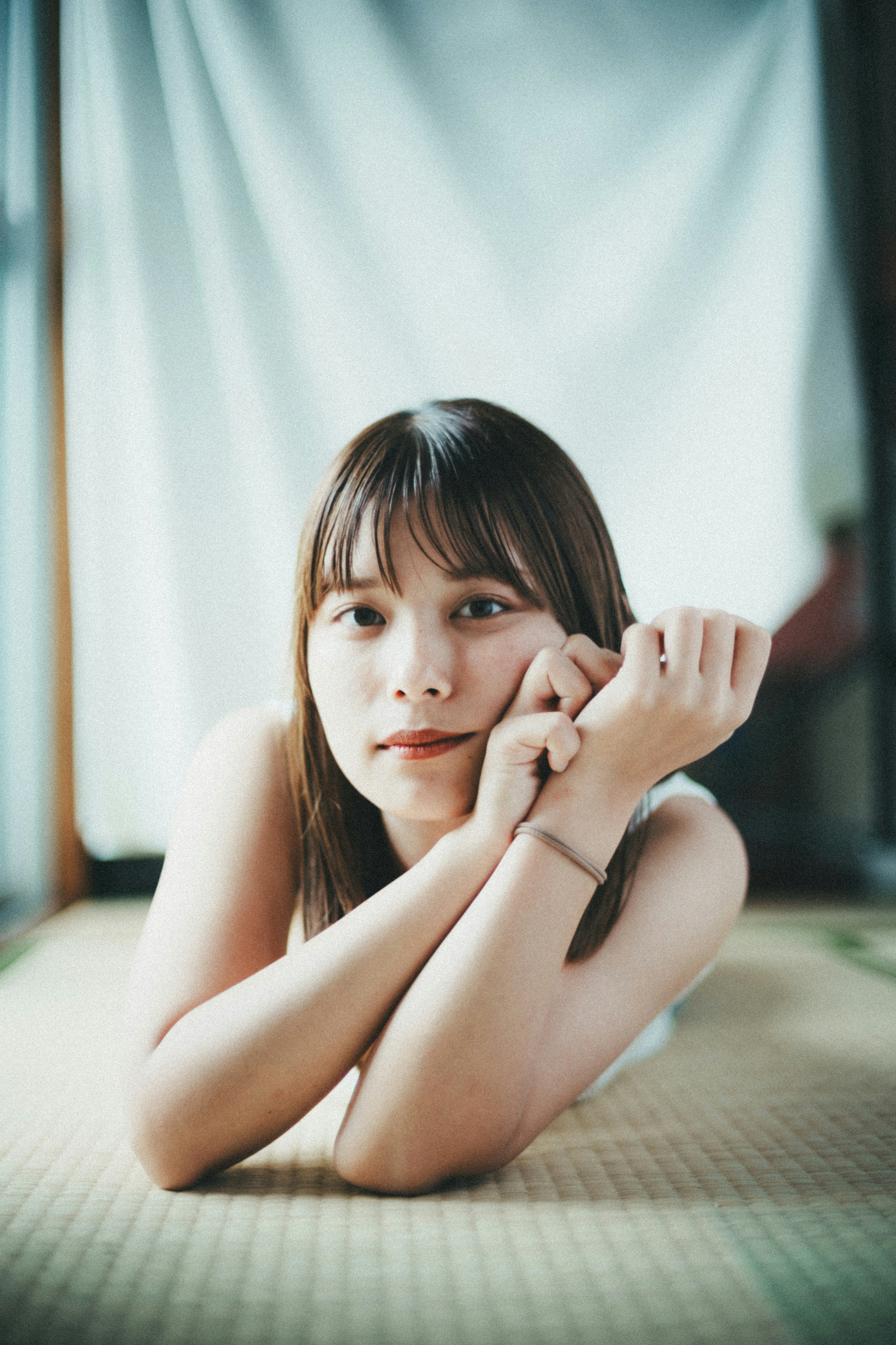 Giovane donna sdraiata su un tatami con un'espressione serena che guarda la macchina fotografica