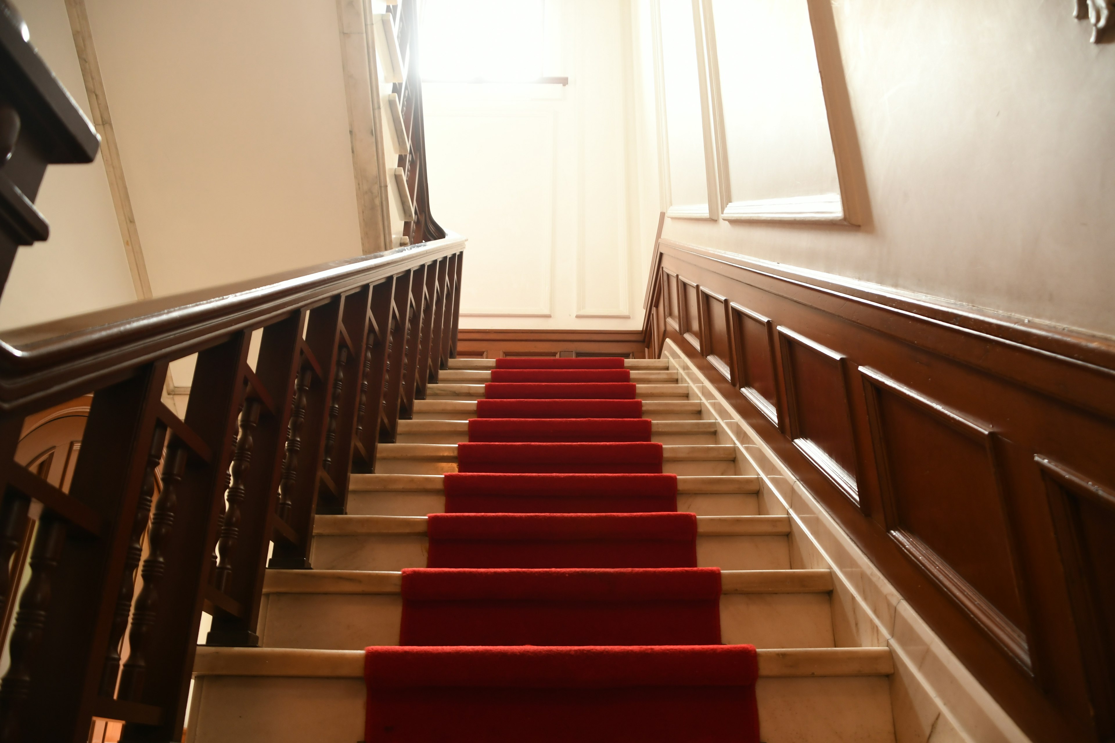 Bild, das eine Aussicht auf eine Treppe mit rotem Teppich und Holzgeländern zeigt