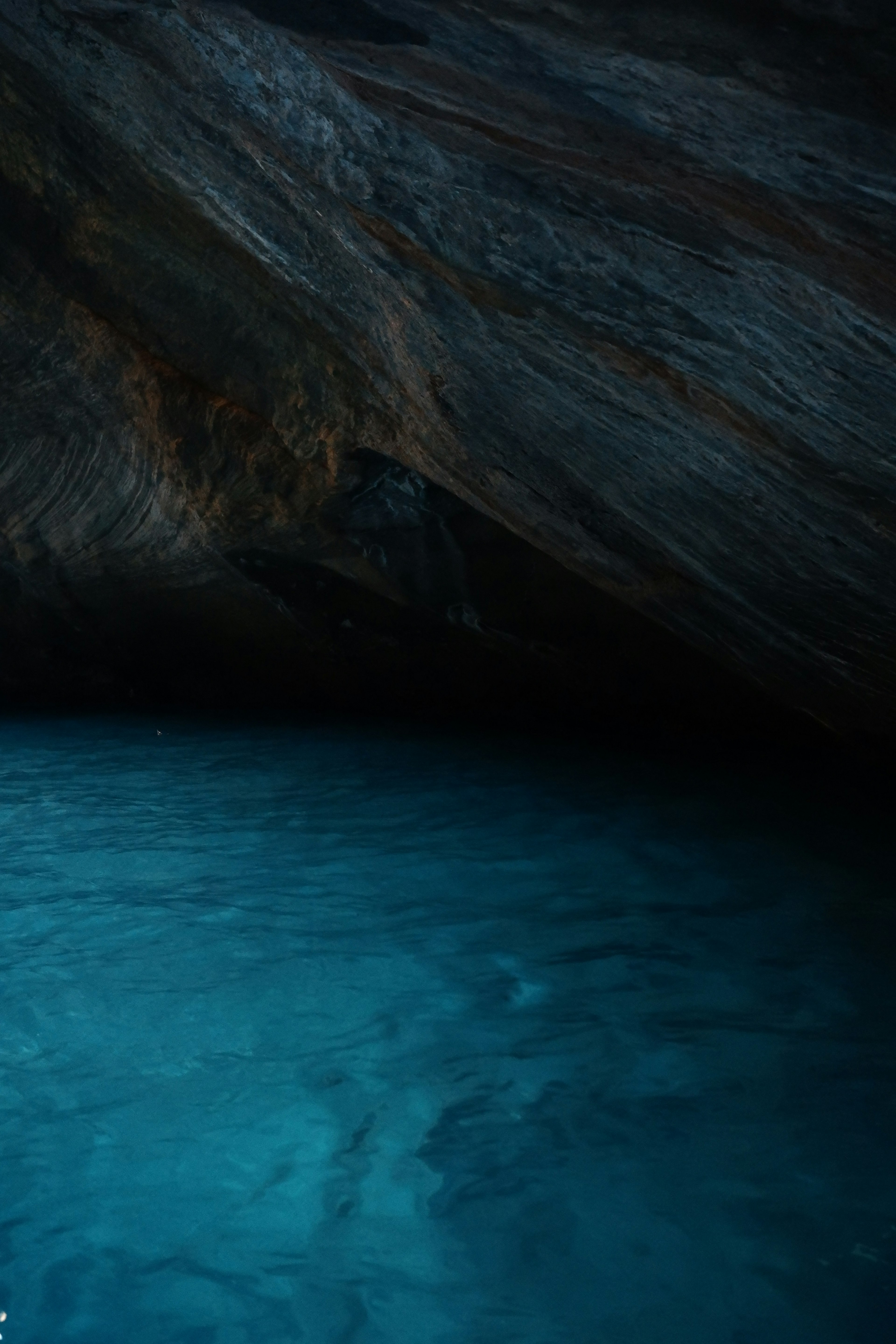 Intérieur d'une grotte avec de l'eau bleue et des formations rocheuses sombres