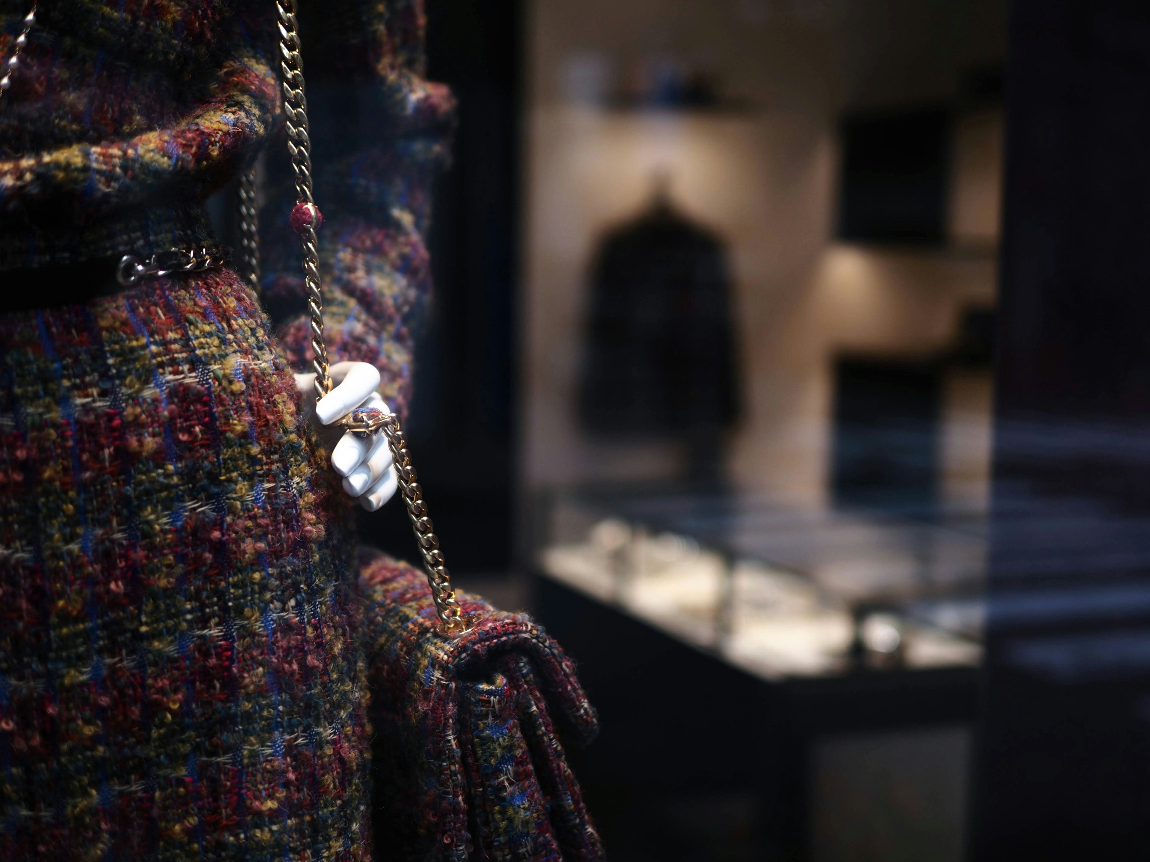 Veste en tweed colorée et sac à main exposés dans une vitrine de magasin