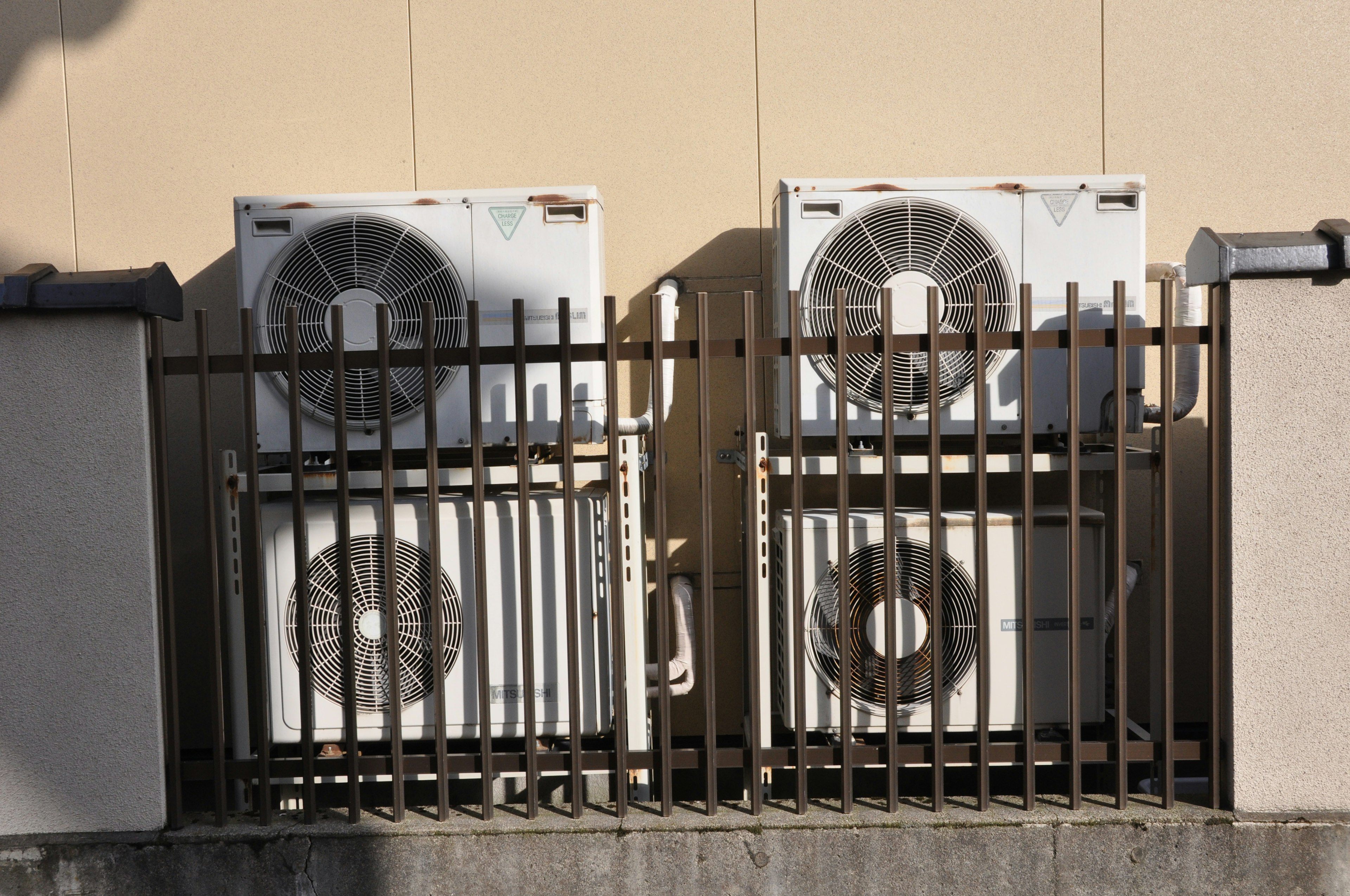 Two air conditioning units enclosed by a fence