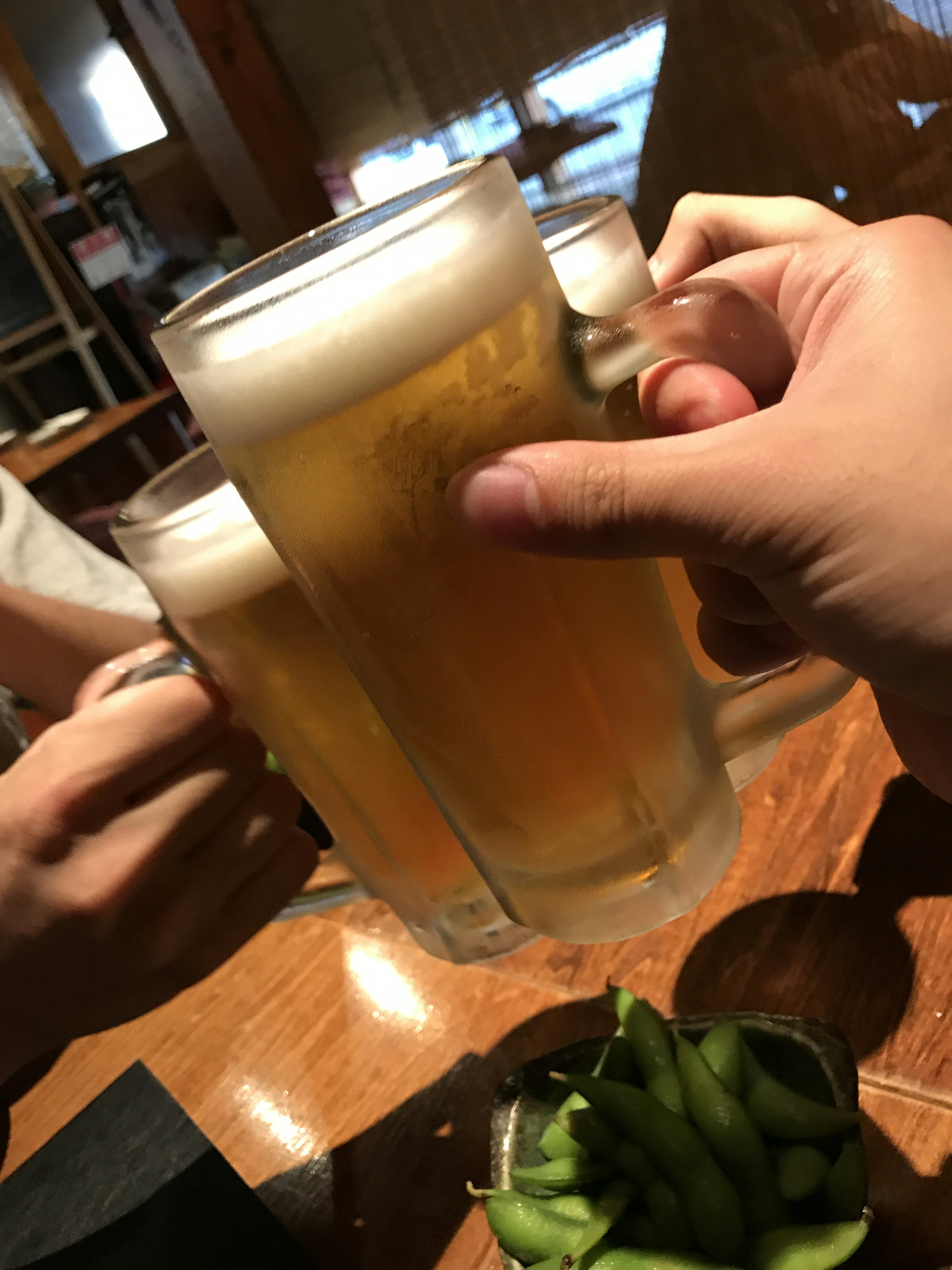 Manos chocando vasos de cerveza en un brindis