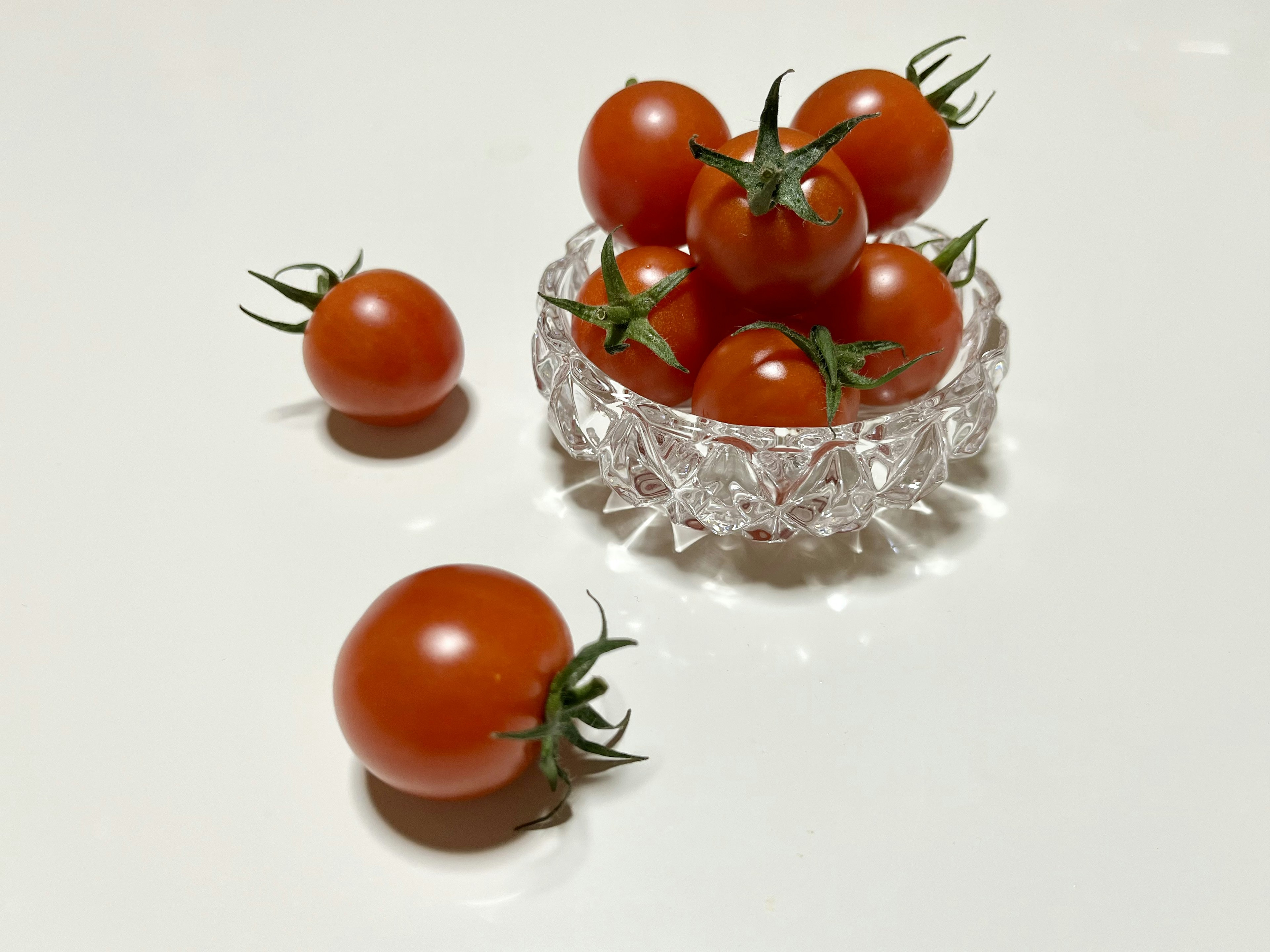 A cluster of small red tomatoes in a clear bowl