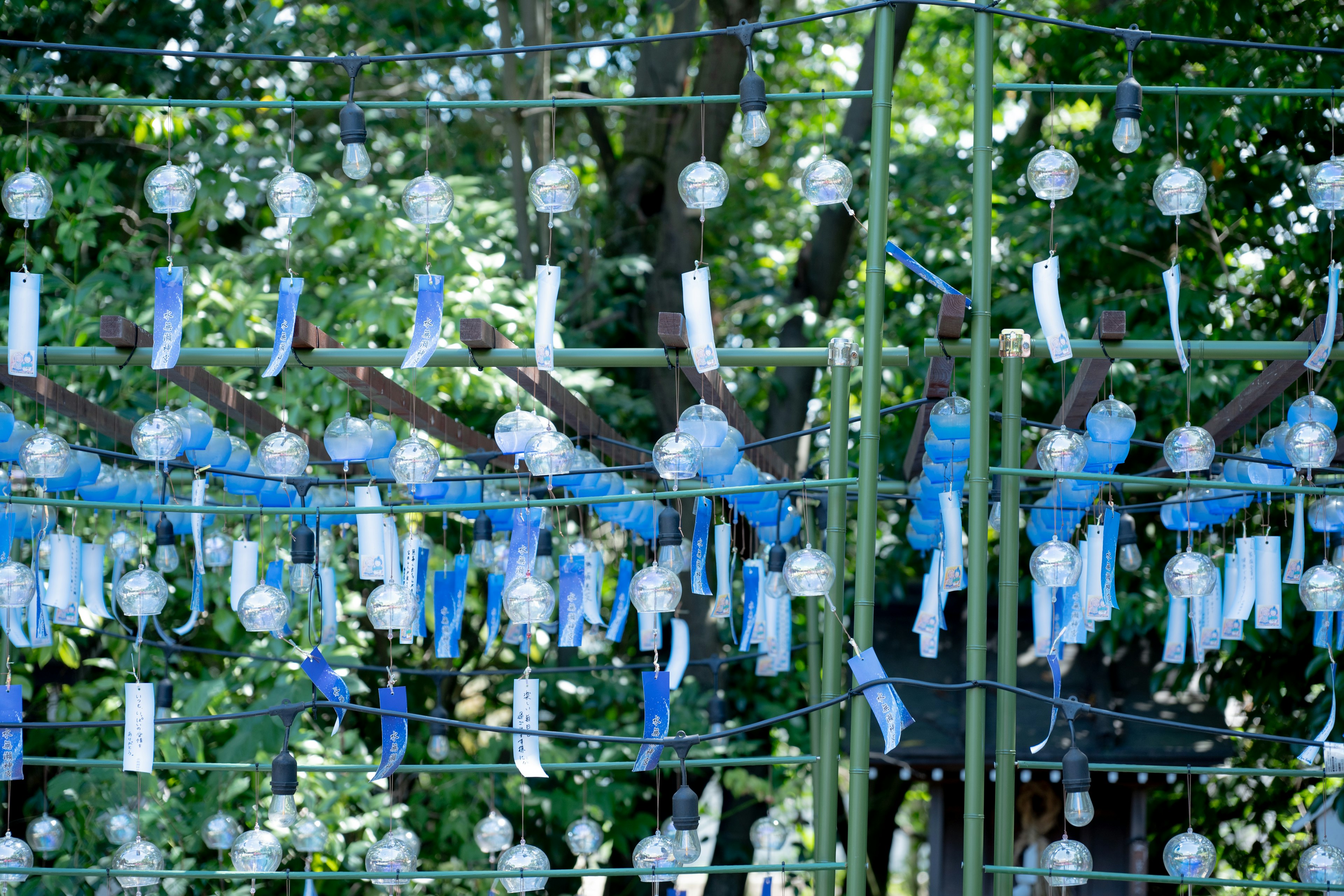 Foto einer Bambusstruktur geschmückt mit blauen Windspielen und weißen Bändern