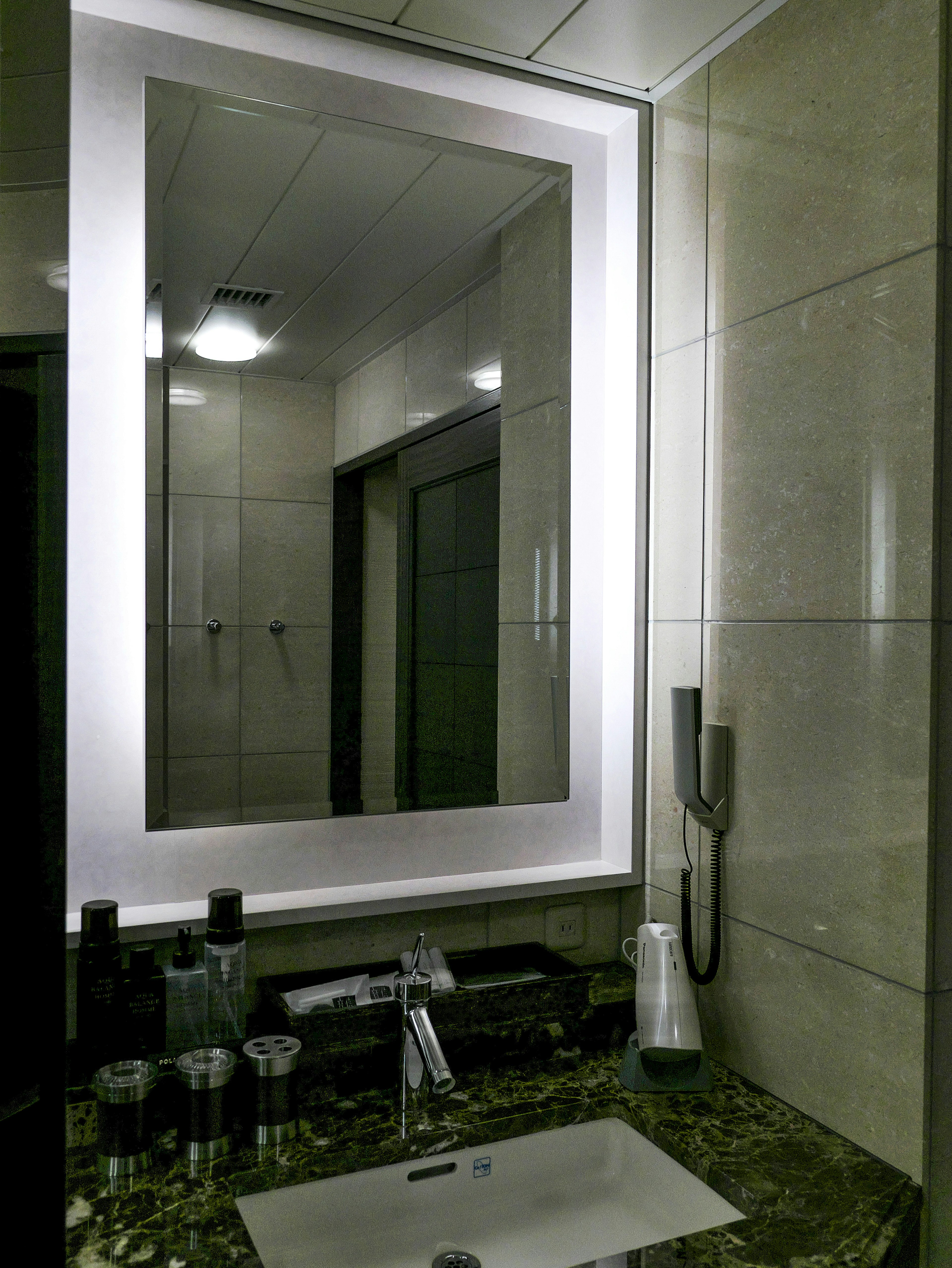 Image d'une salle de bain moderne avec un miroir bien éclairé et un lavabo