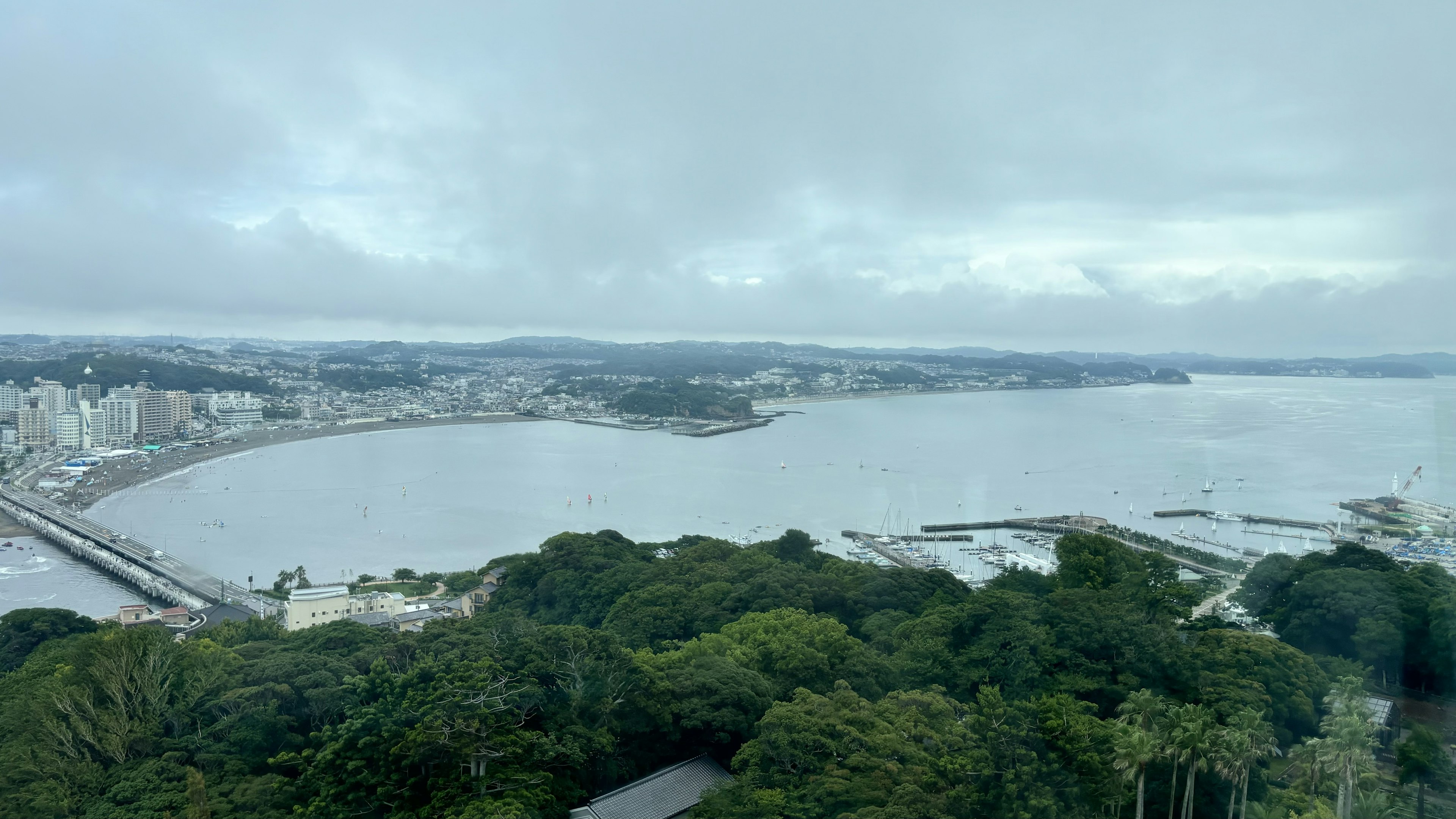 海与城市的全景 阴云密布的天空 茂密的绿树和海岸线