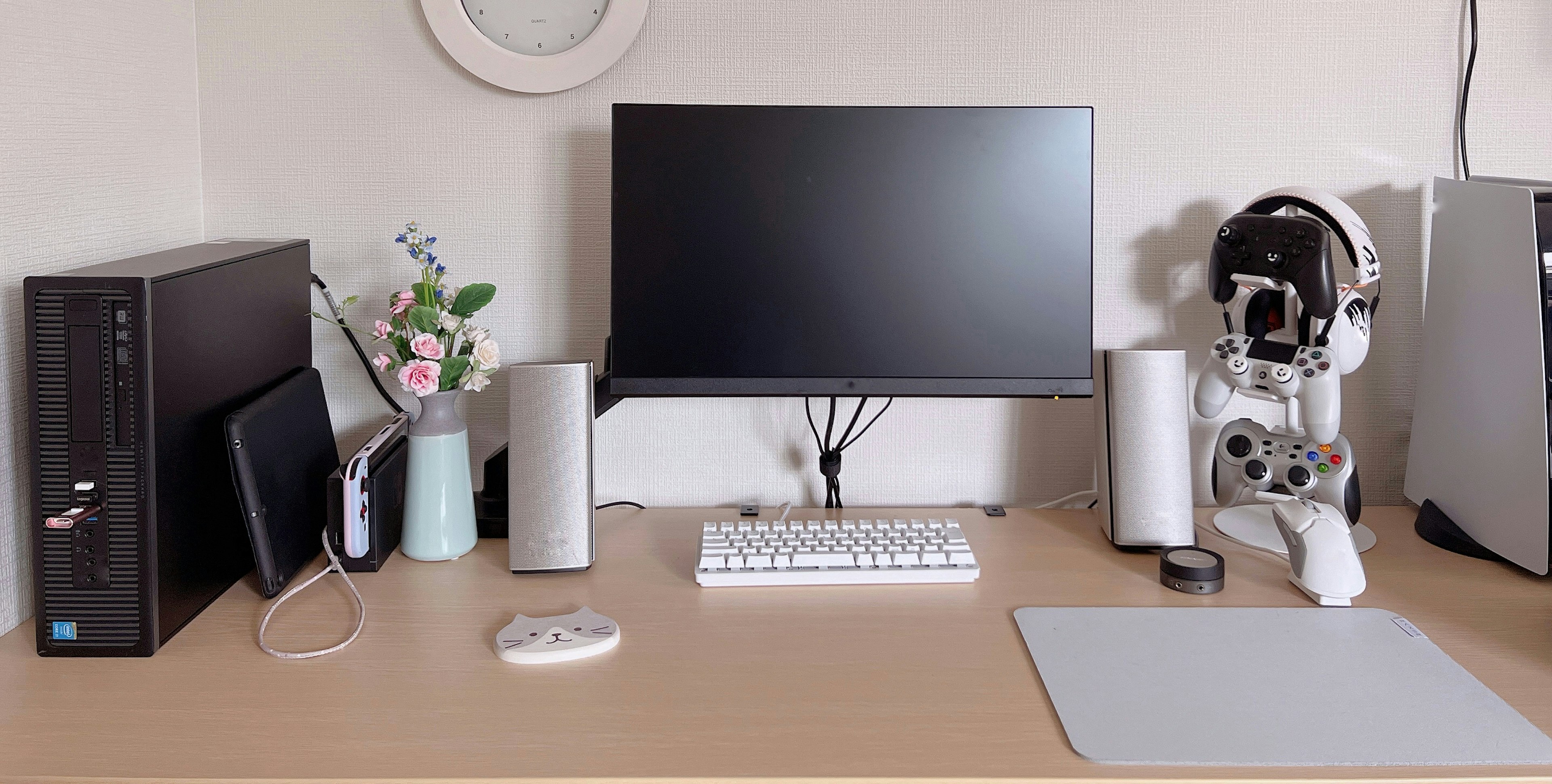 Setup da scrivania minimalista con monitor e composizione floreale