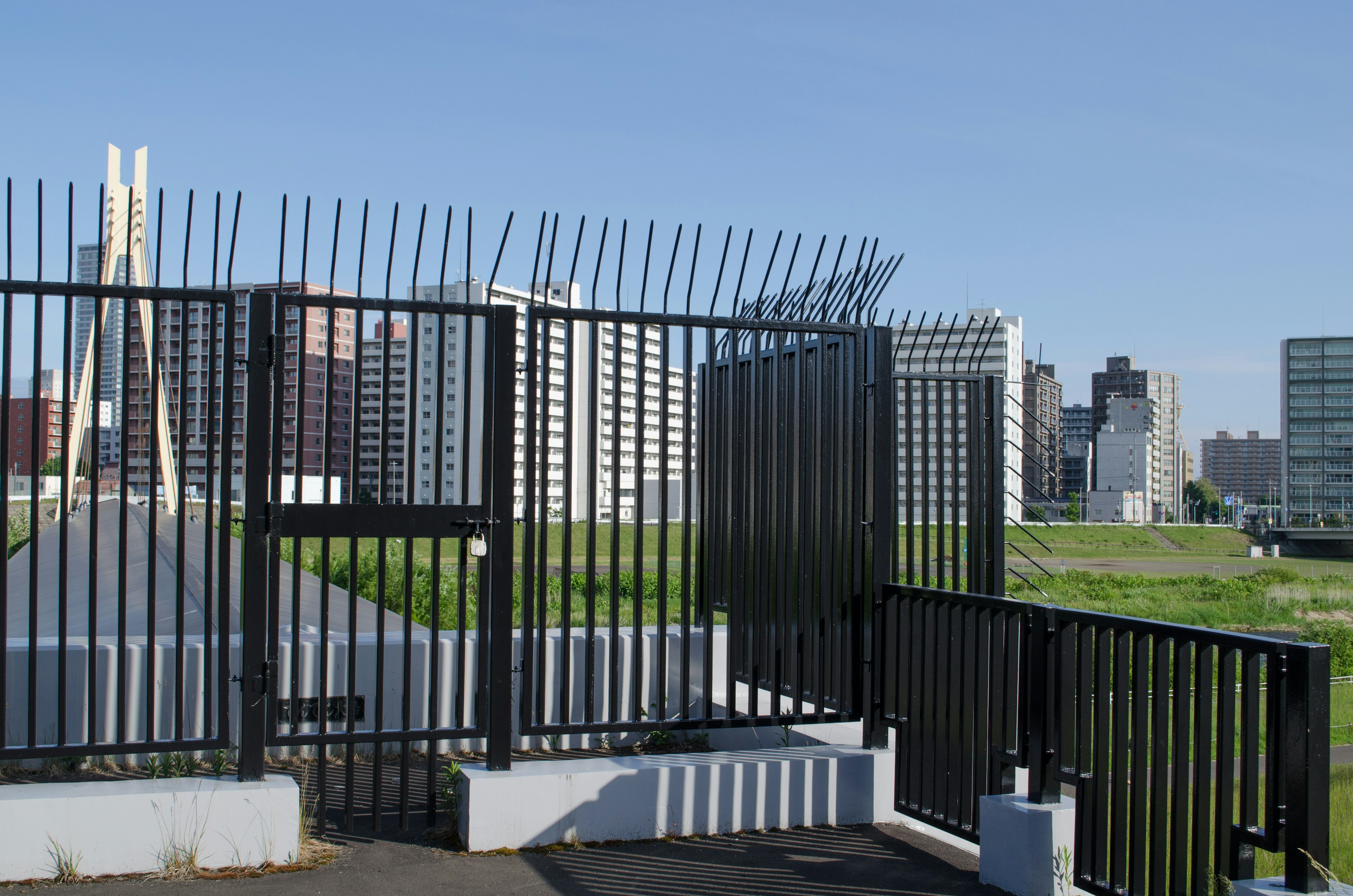 Park entrance with tall fence and city skyline in background