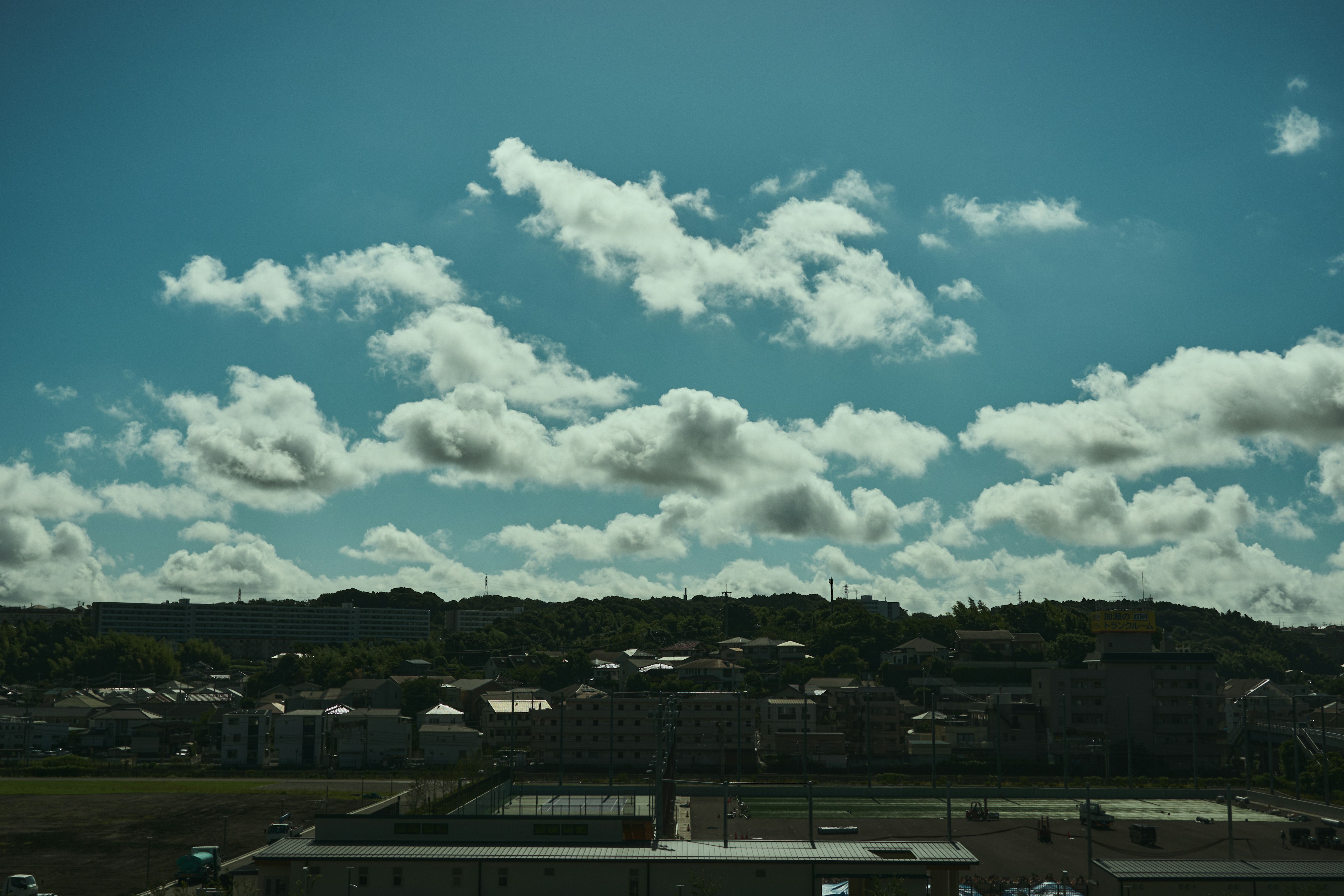 青空と白い雲のある風景の写真 住宅や緑豊かな丘が見える