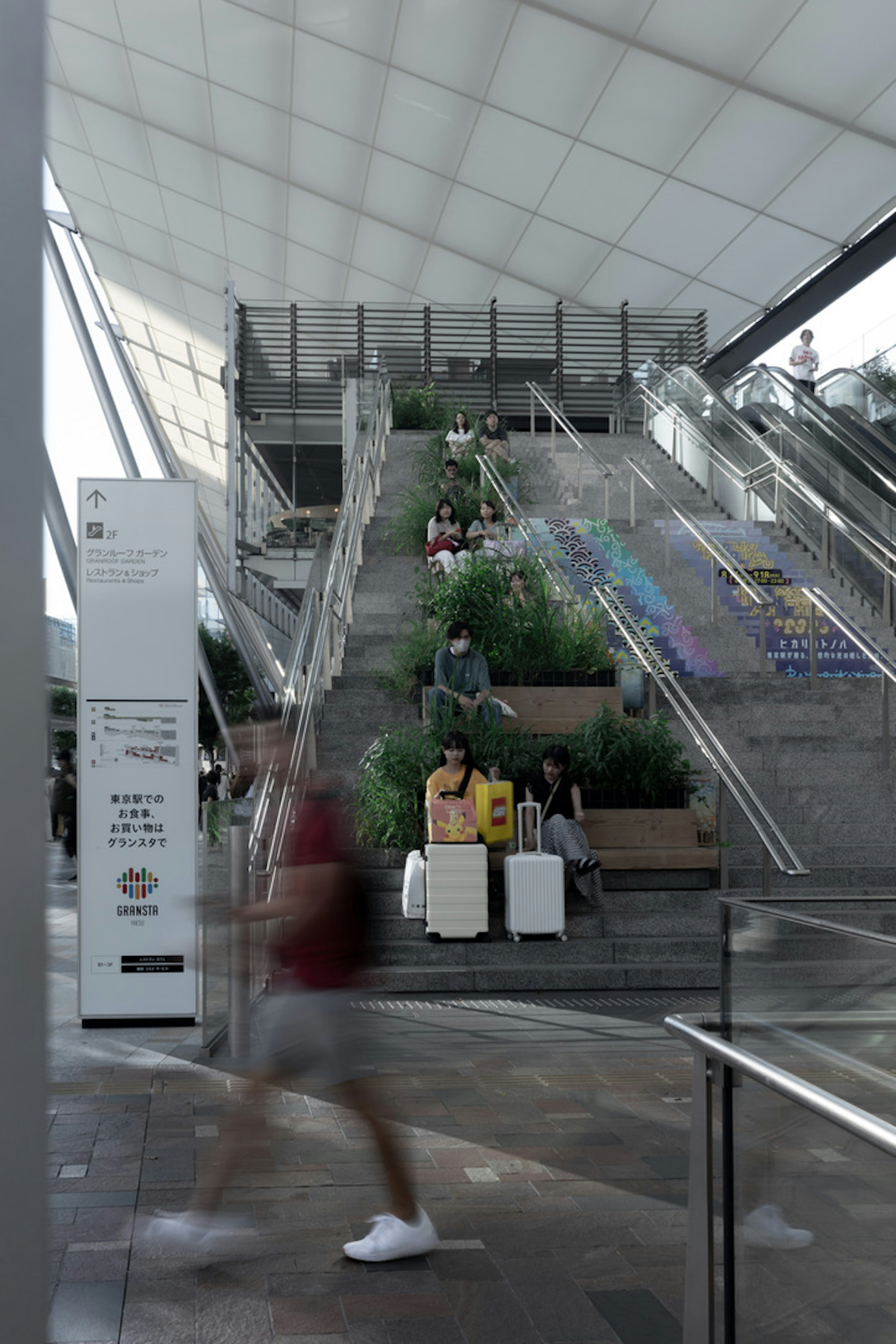 現代的な駅の内部でエスカレーターと緑の植物が見える