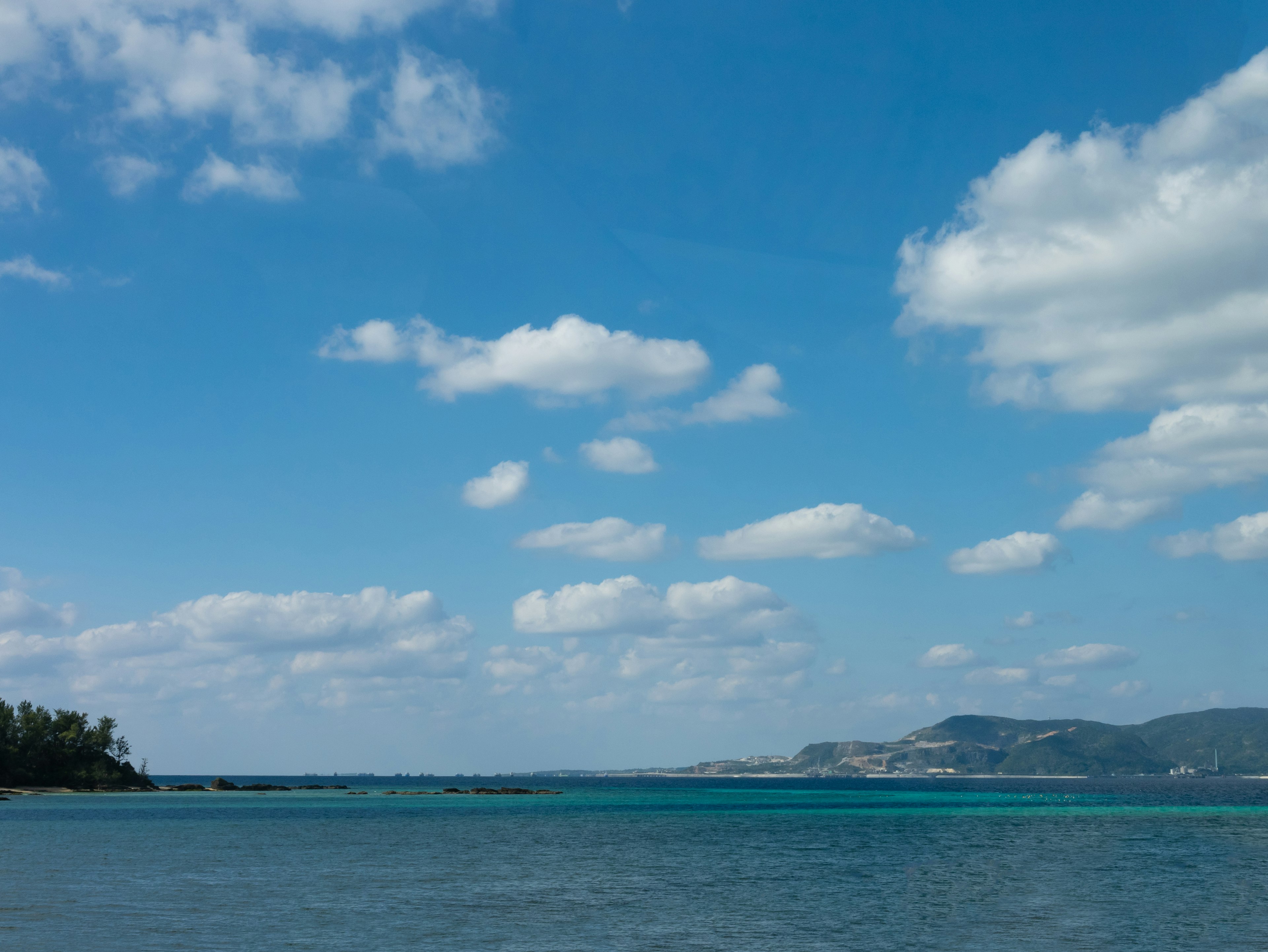 Pemandangan laut biru di bawah langit yang dipenuhi awan putih