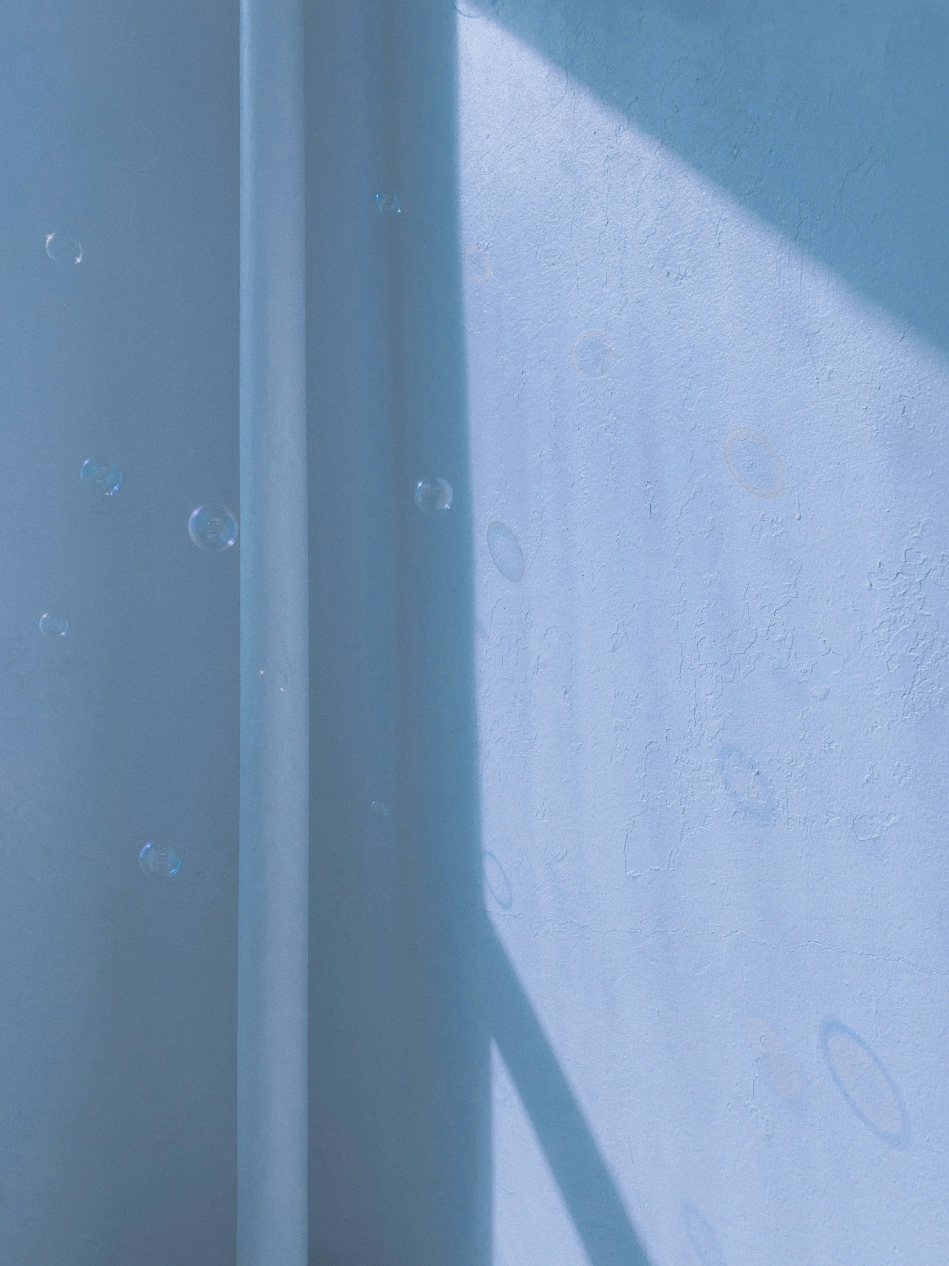 Surface with water droplets and light shadow on a blue background