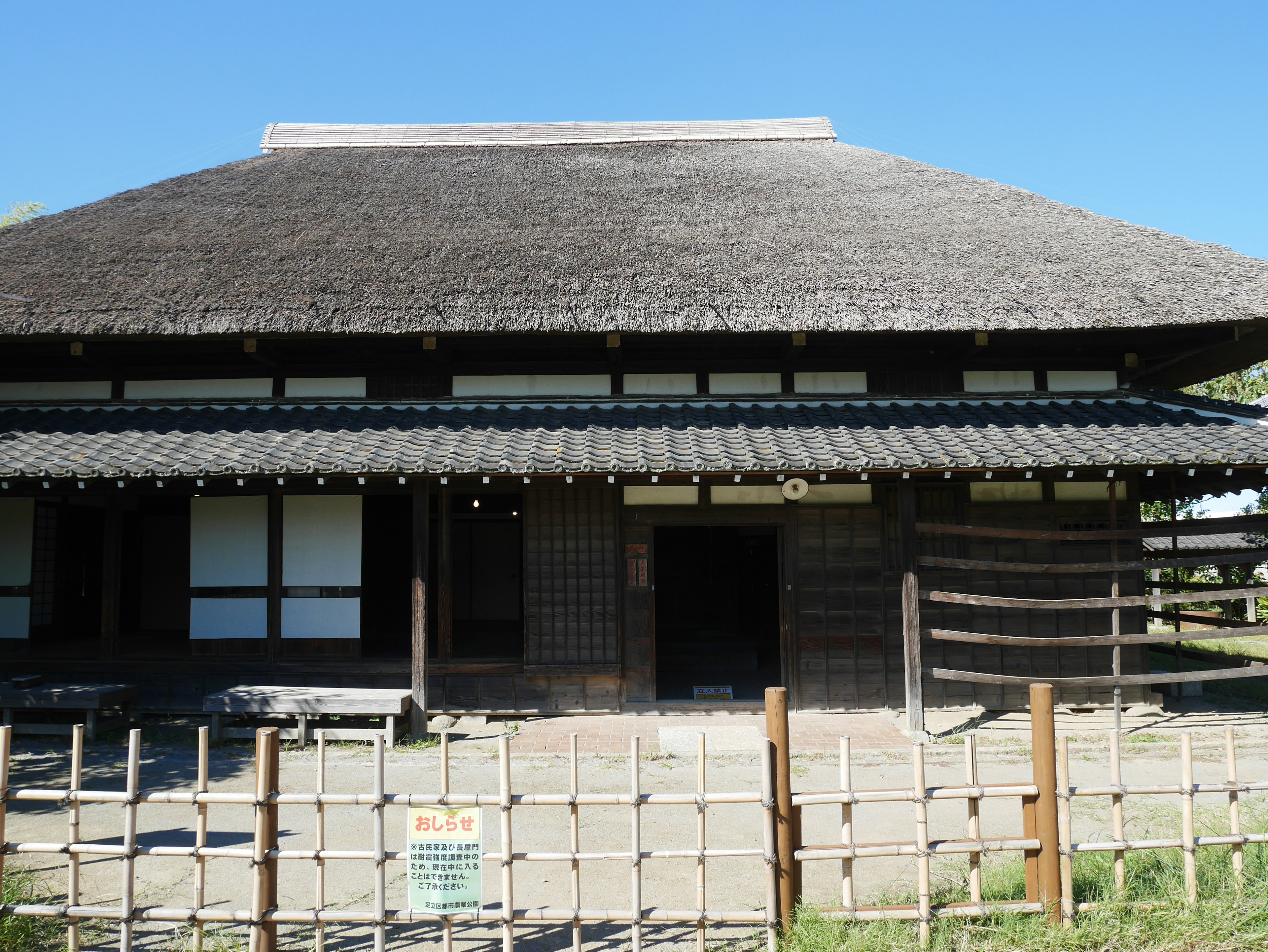 传统日本建筑外观，茅草屋顶木结构在蓝天之下