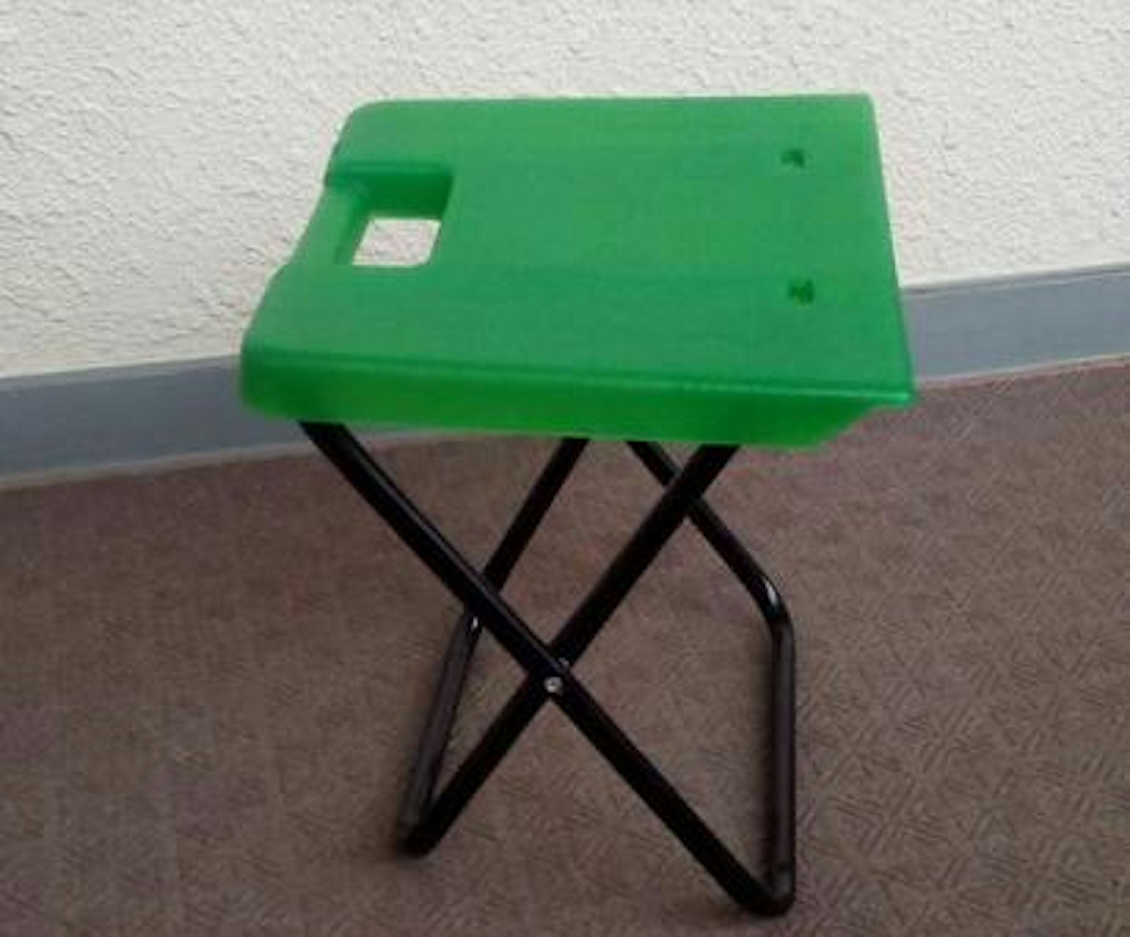 Green folding stool with black metal legs