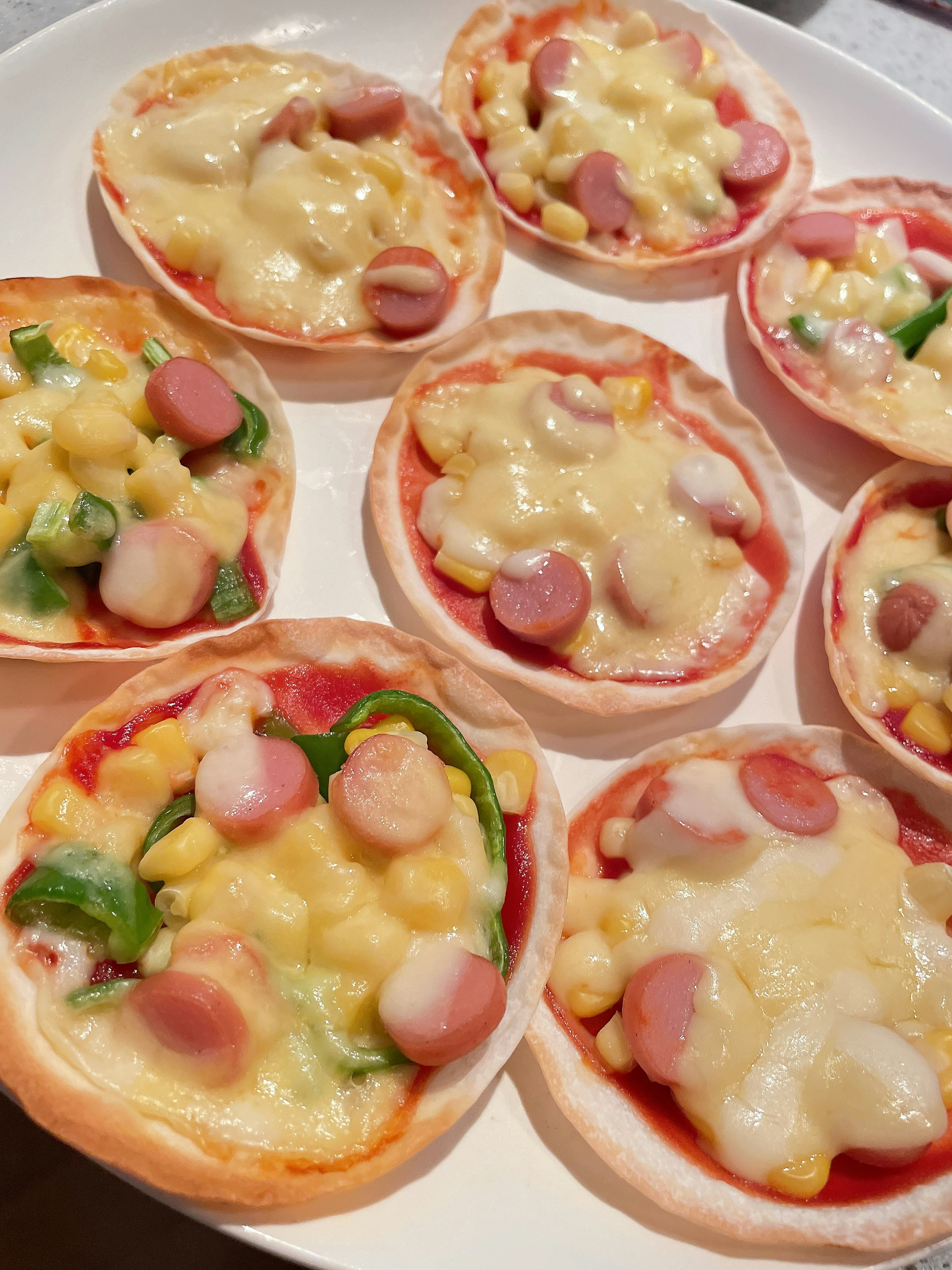 Platter of mini pizzas topped with cheese and sausages