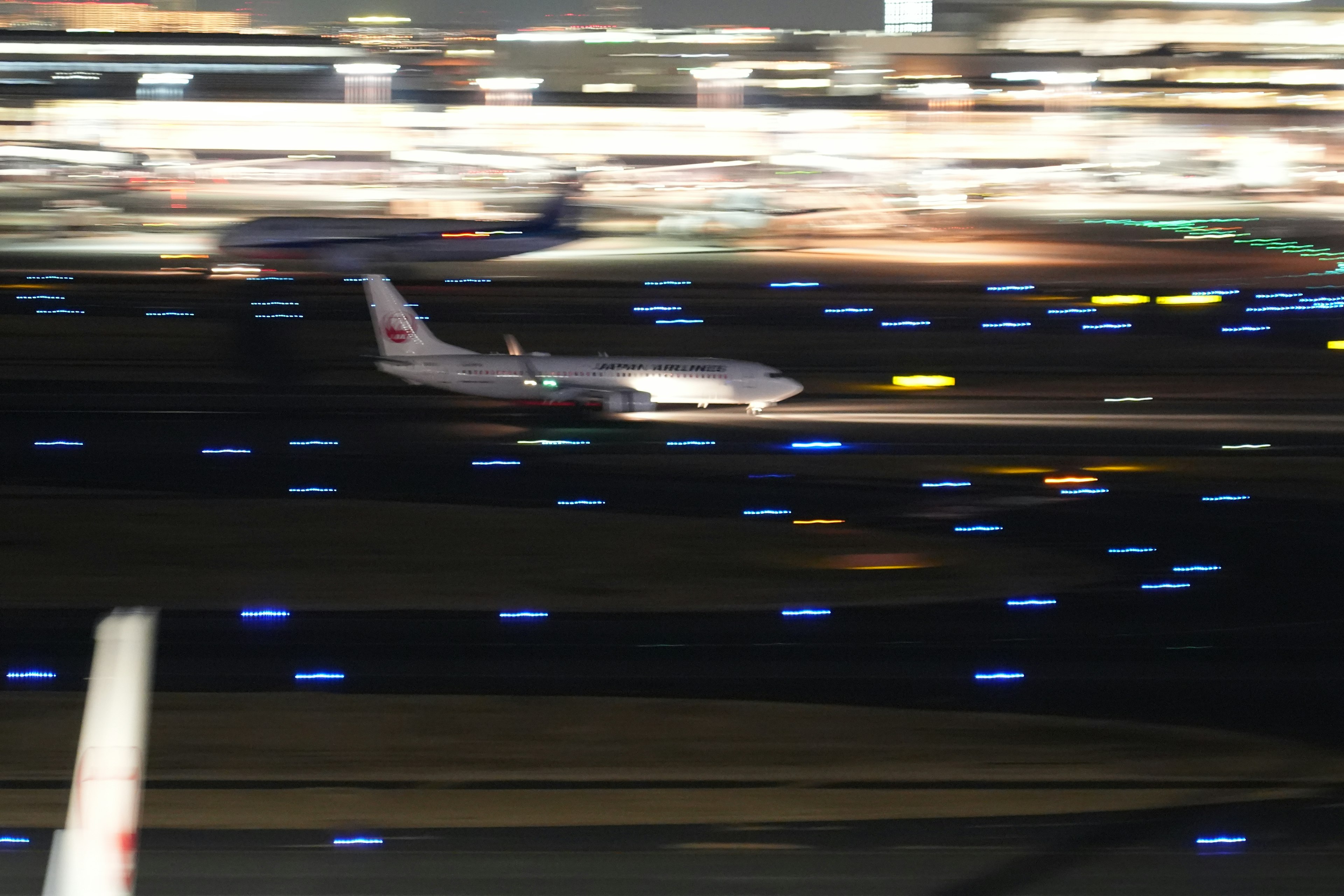 Un avión aterrizando en una pista por la noche con luces iluminadas