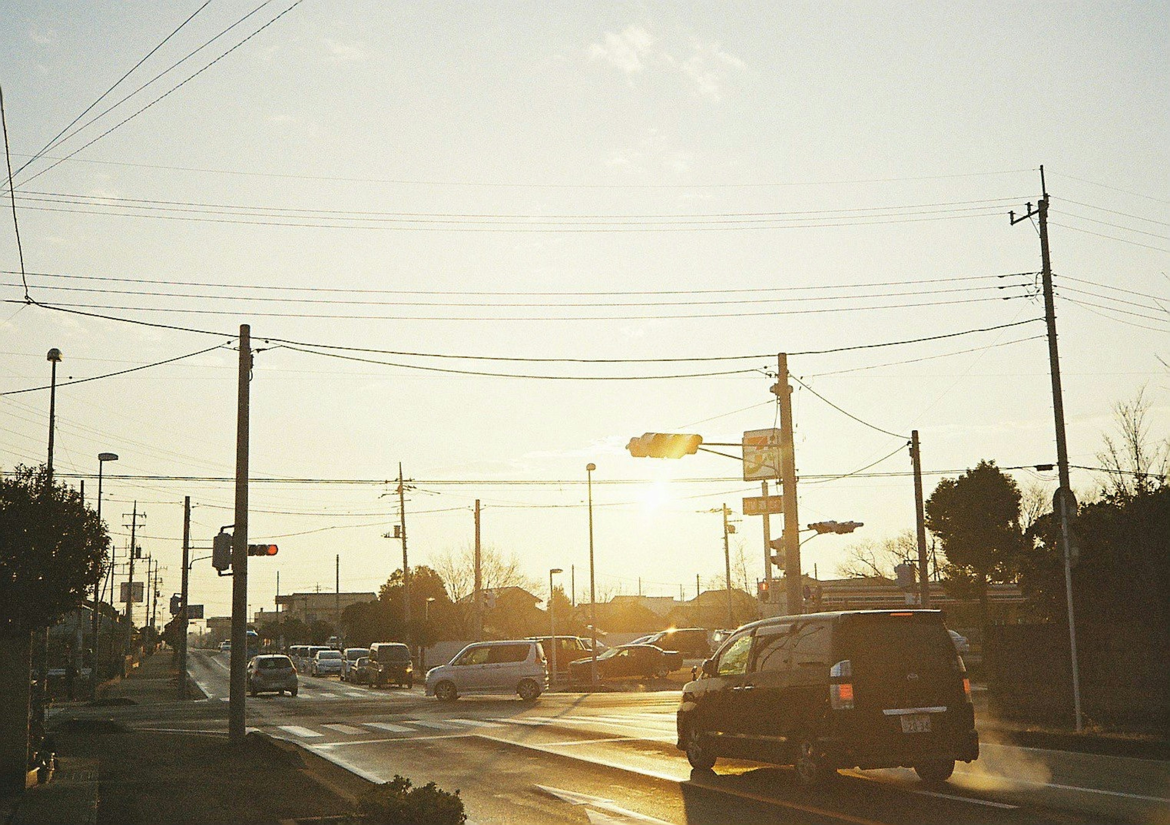 Scena di strada al tramonto con auto e pali della luce