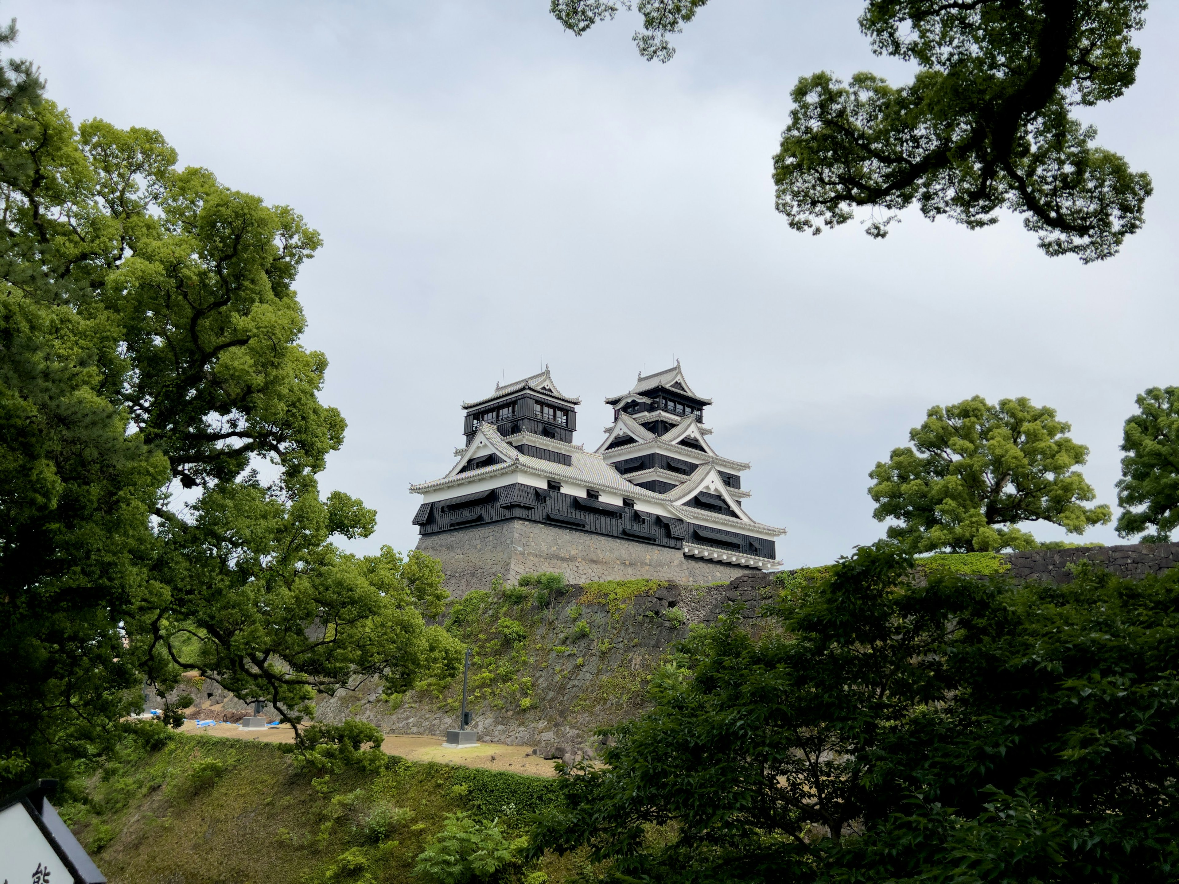 Schöne Fassade der Burg Kumamoto umgeben von üppigen Bäumen