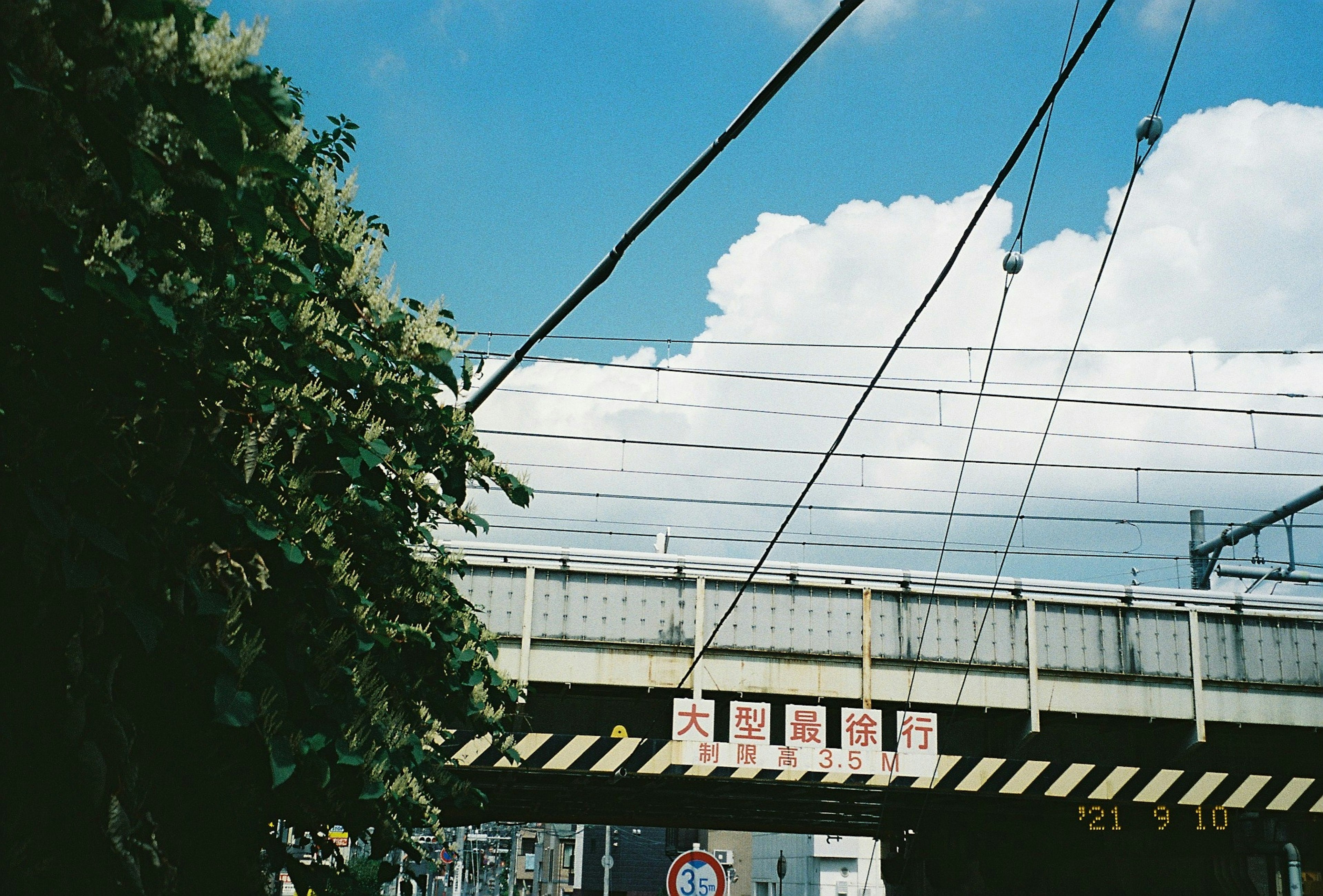 青空の下にある鉄道の高架橋と電線が見える風景