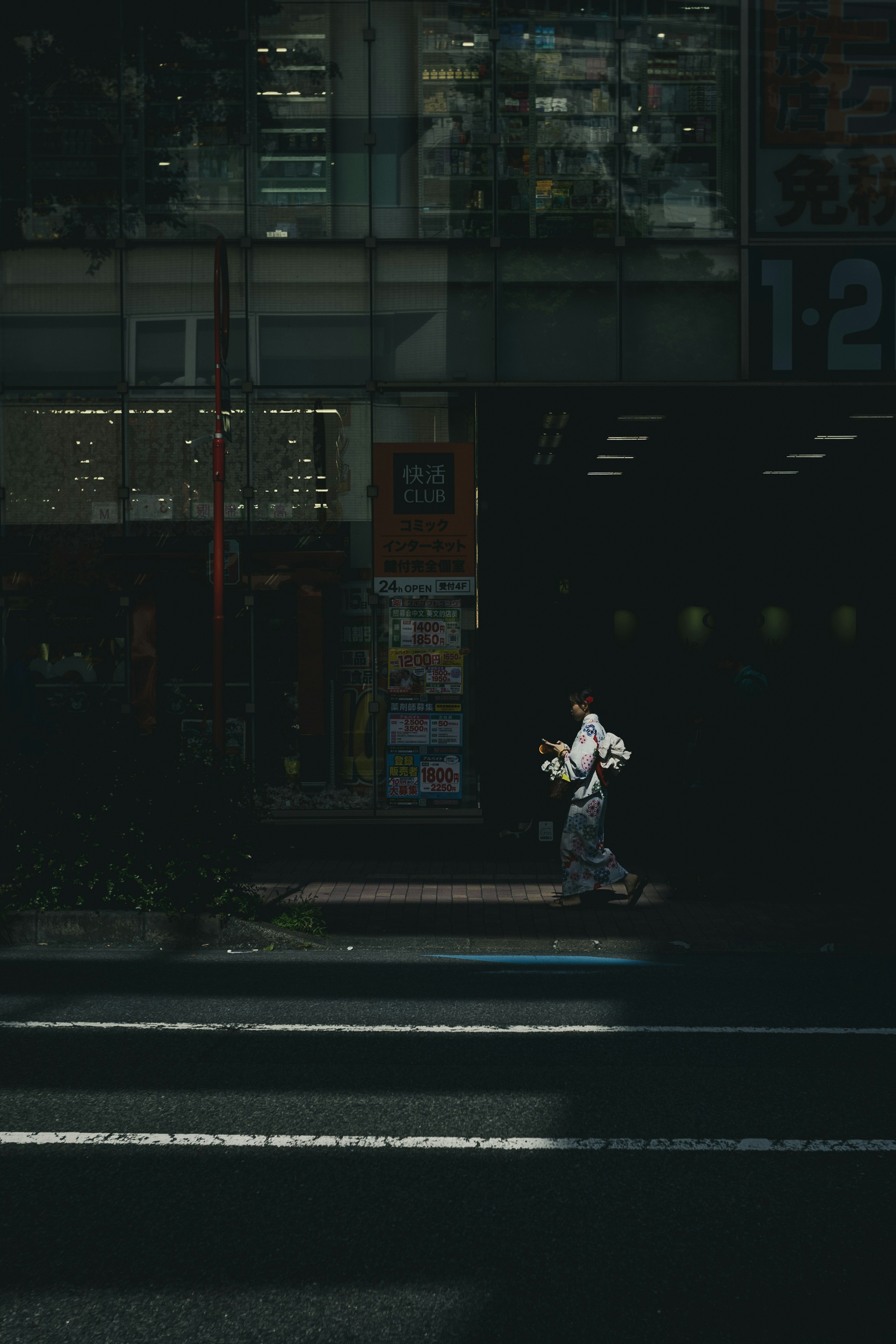 Una figura con ropa blanca caminando en una esquina de calle poco iluminada