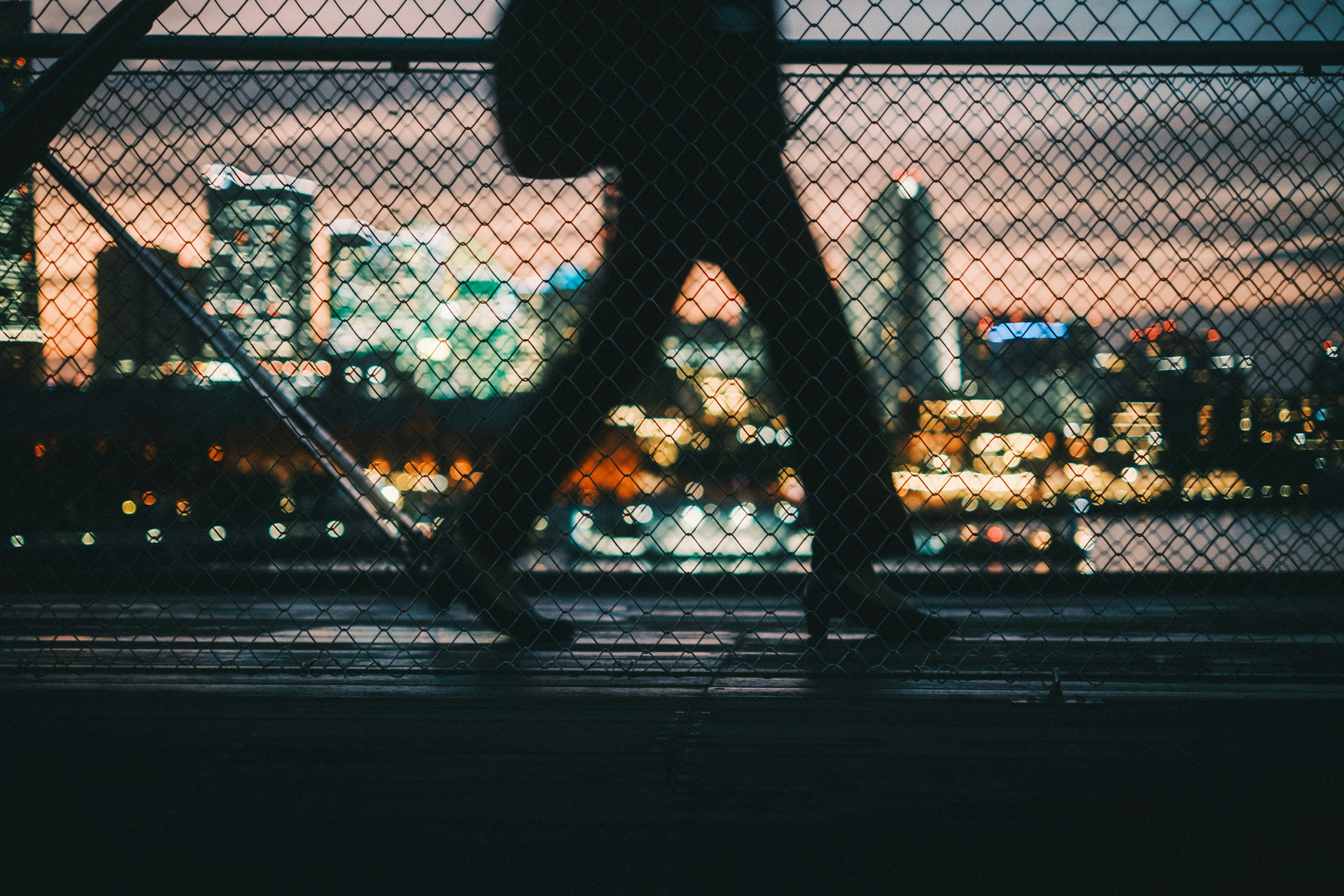 Silueta de una persona caminando contra el horizonte urbano al atardecer