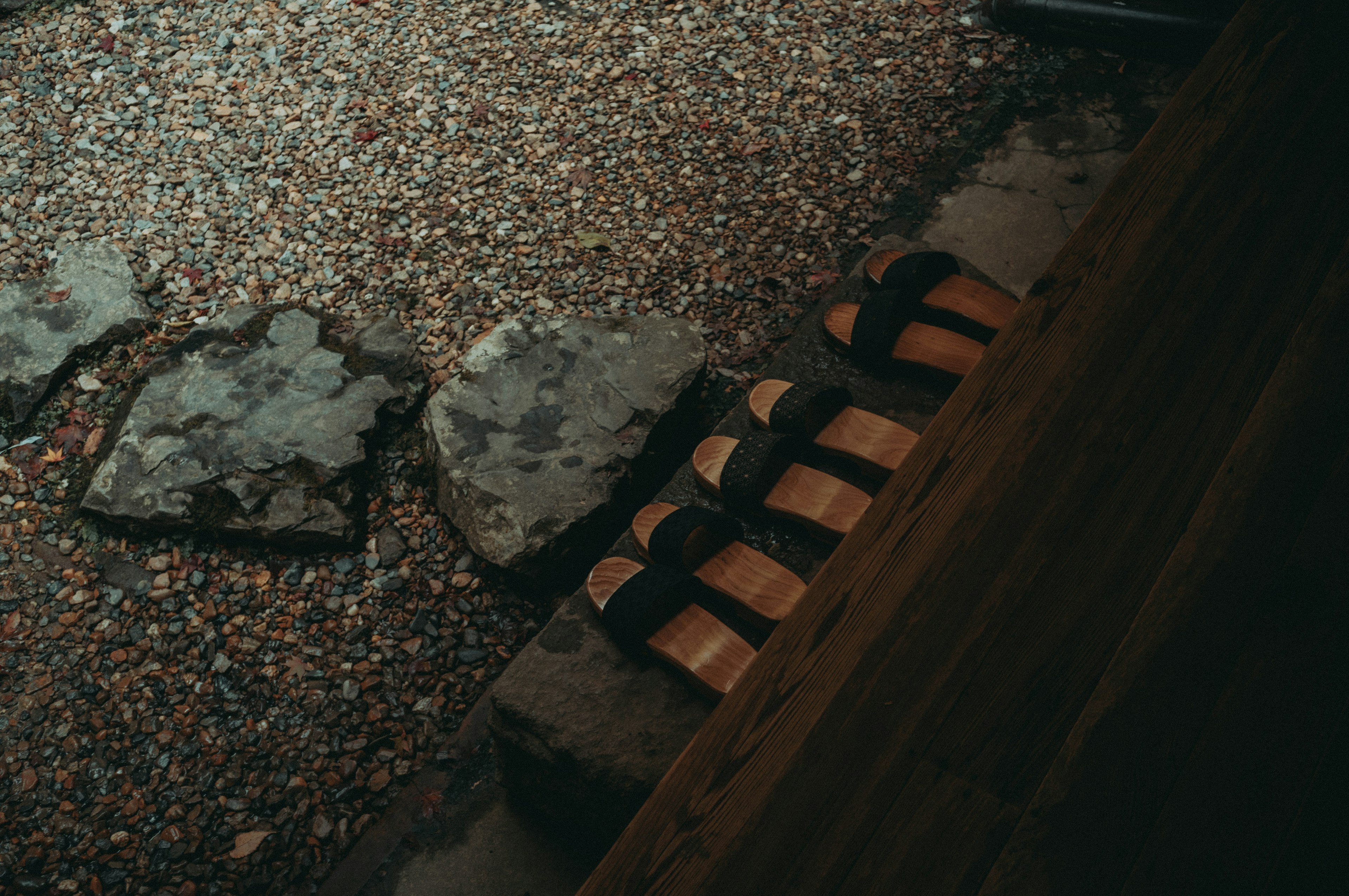 Sandalias de tiras negras colocadas sobre piedras con suelo de grava