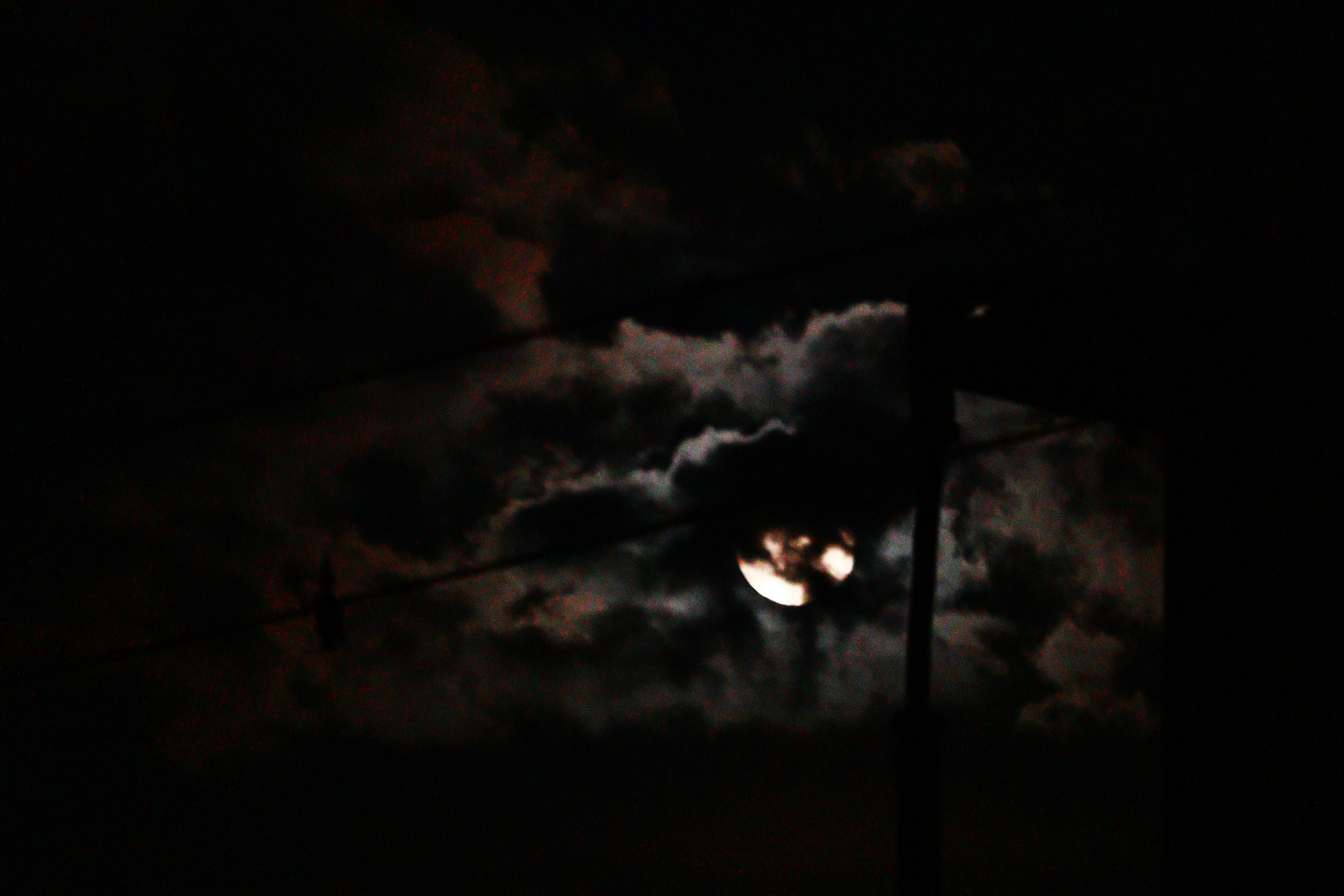 Moon partially obscured by clouds in a dark sky