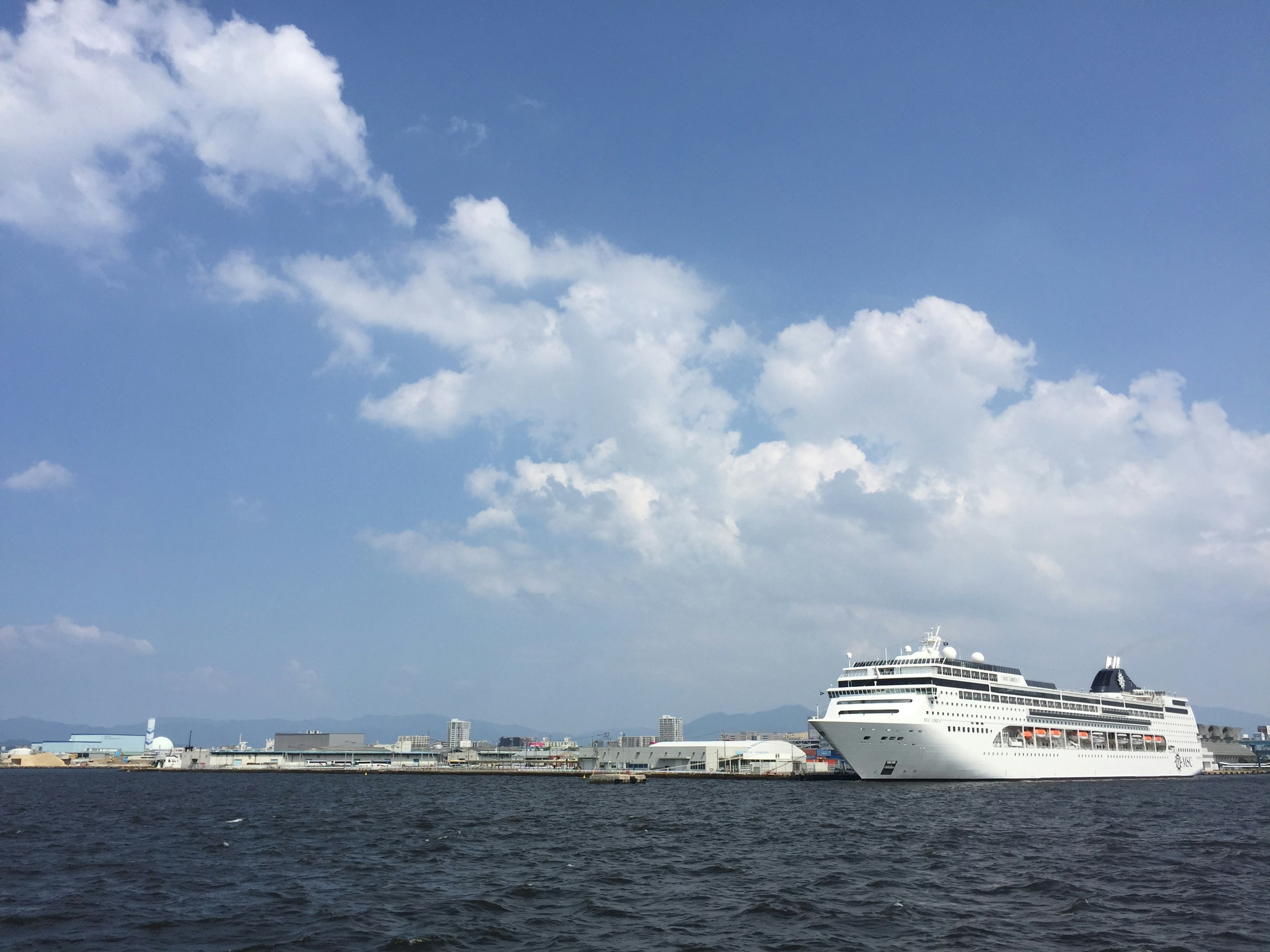 青い空と白い雲の下に停泊する豪華客船