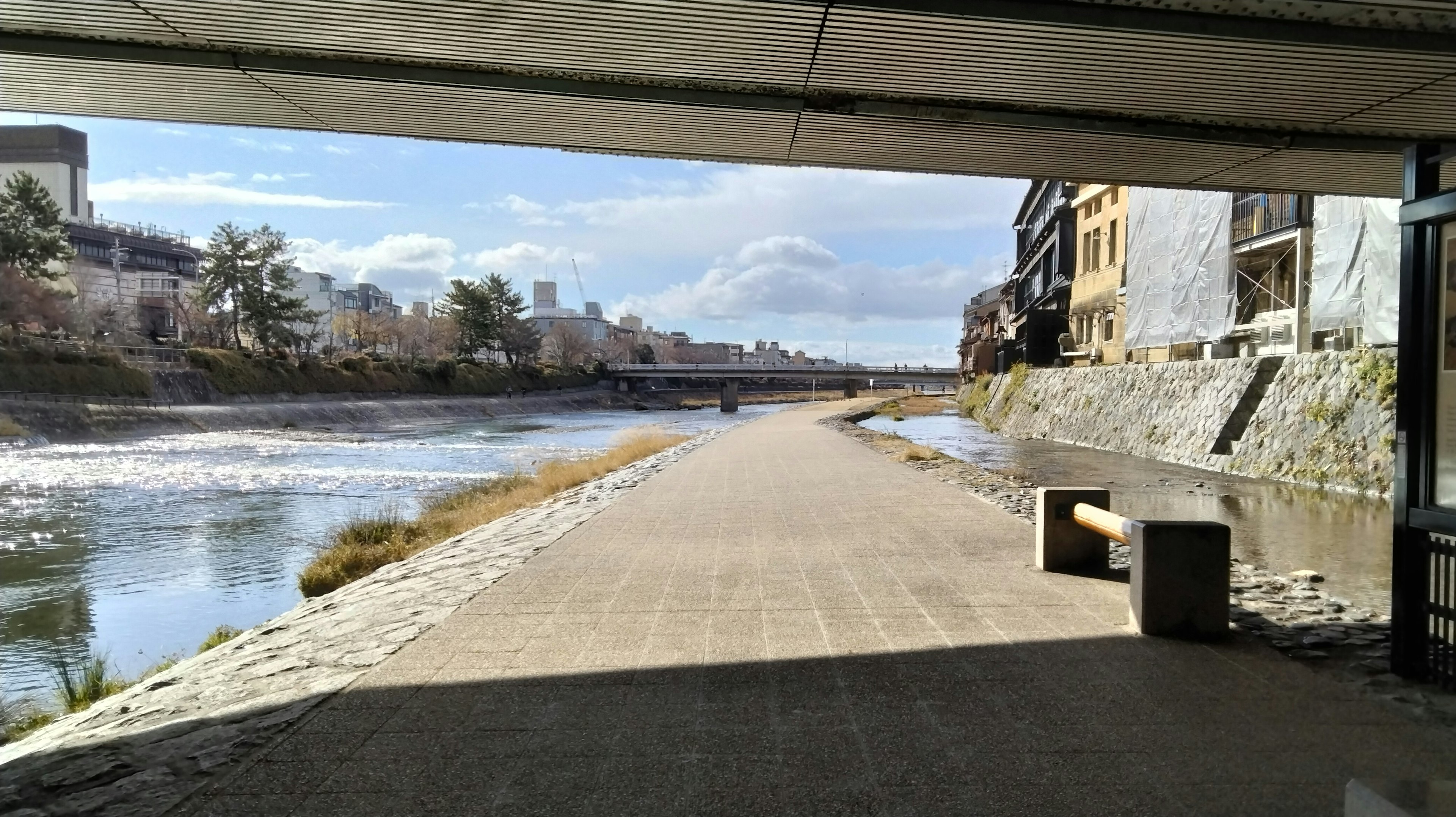 Malerei von einem Gehweg am Fluss unter einer Brücke Natürliches Licht und blauer Himmel