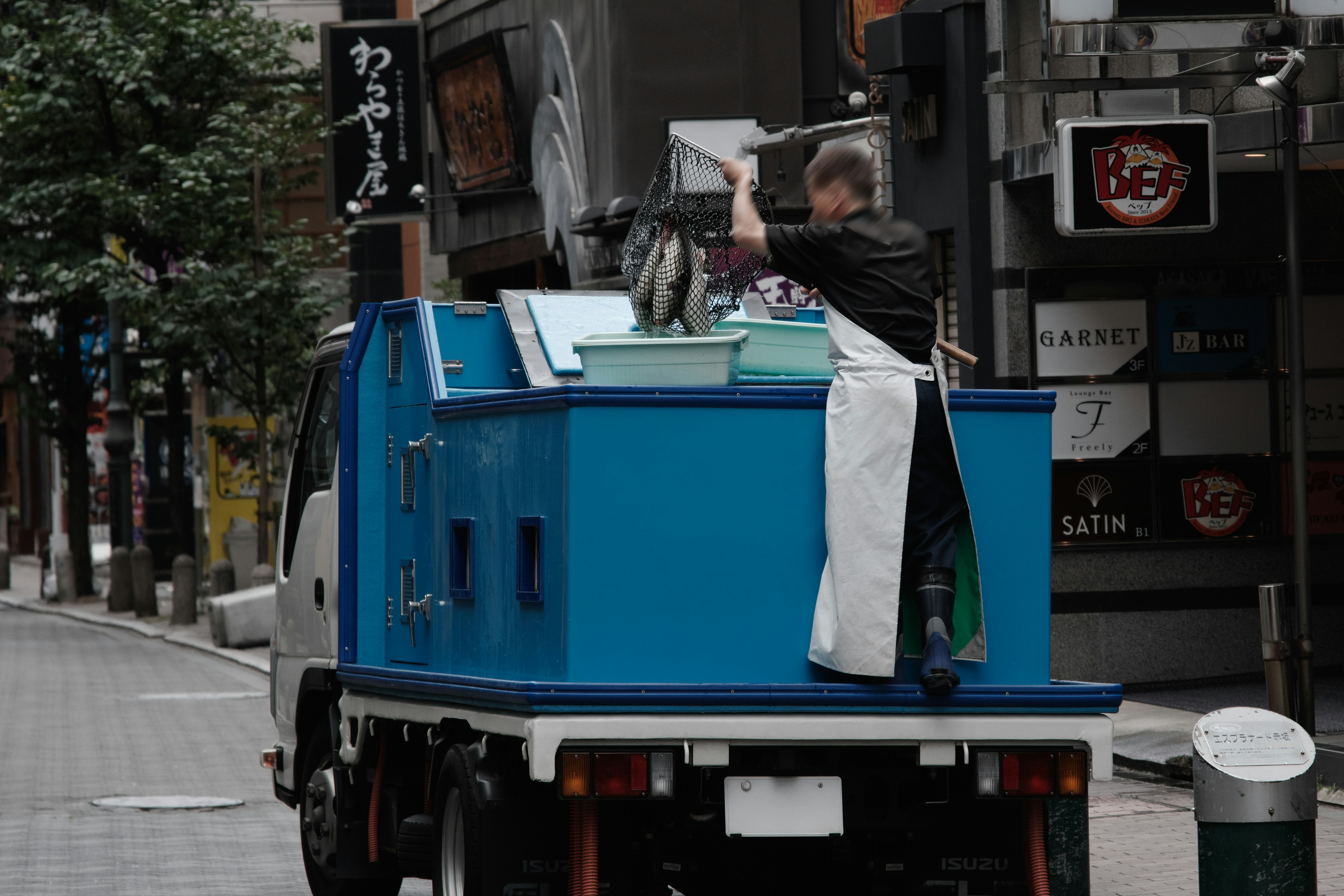 Mann arbeitet auf einem blauen Lastwagen in einer Stadtstraße