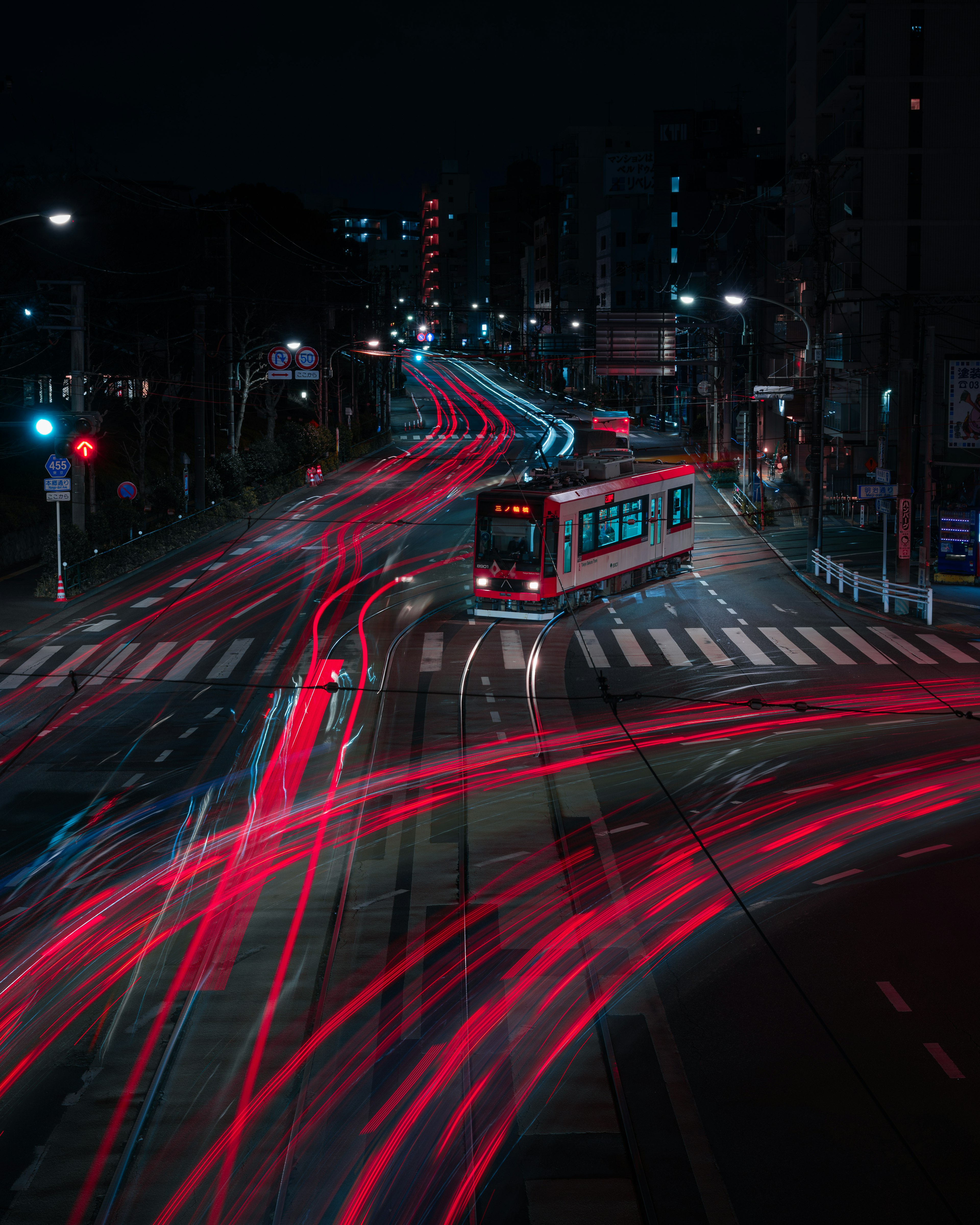 夜間繁忙交叉口的電車和紅色藍色光線的軌跡