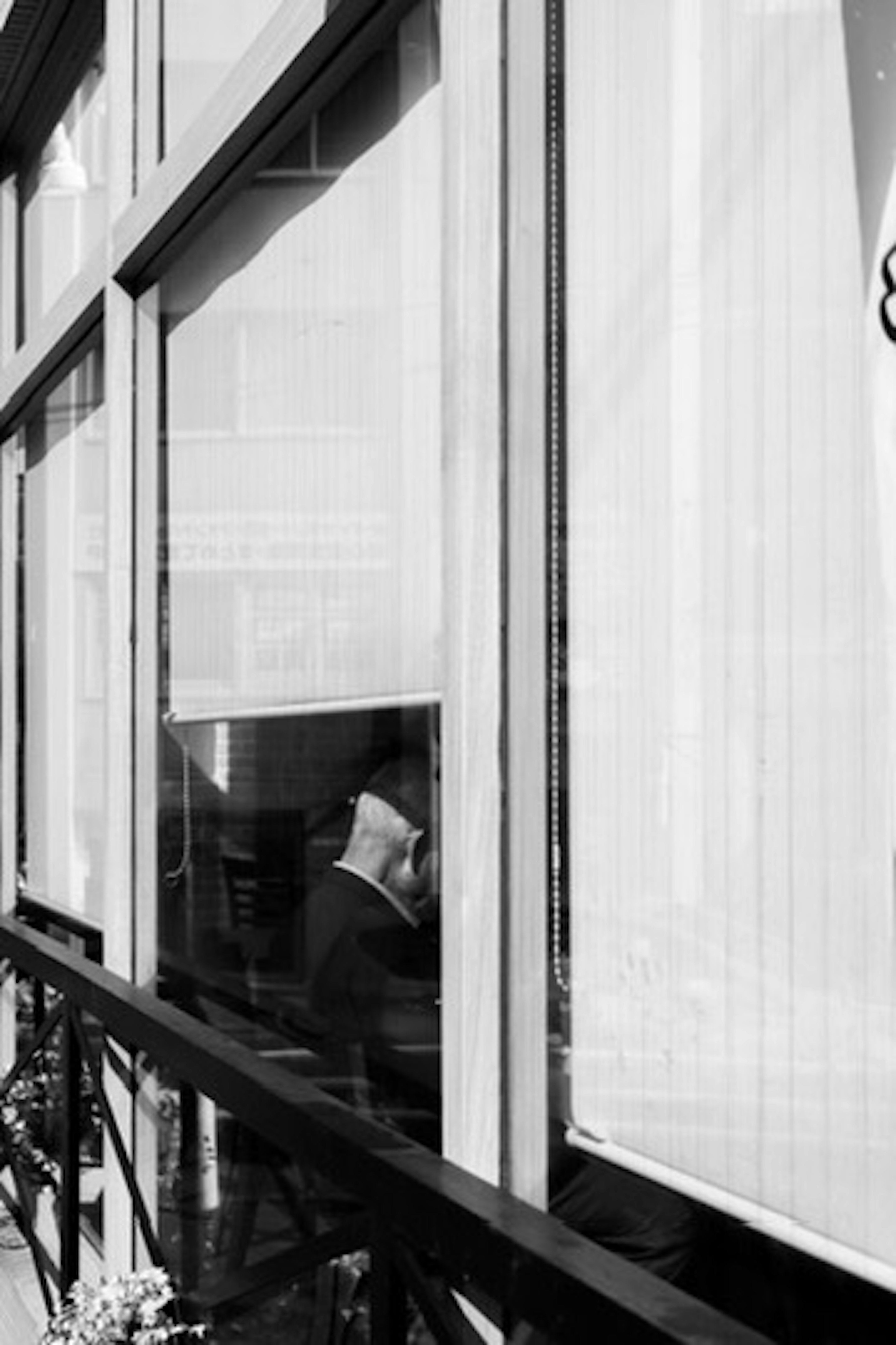 Una escena de una persona sentada visible a través de una ventana en una foto en blanco y negro