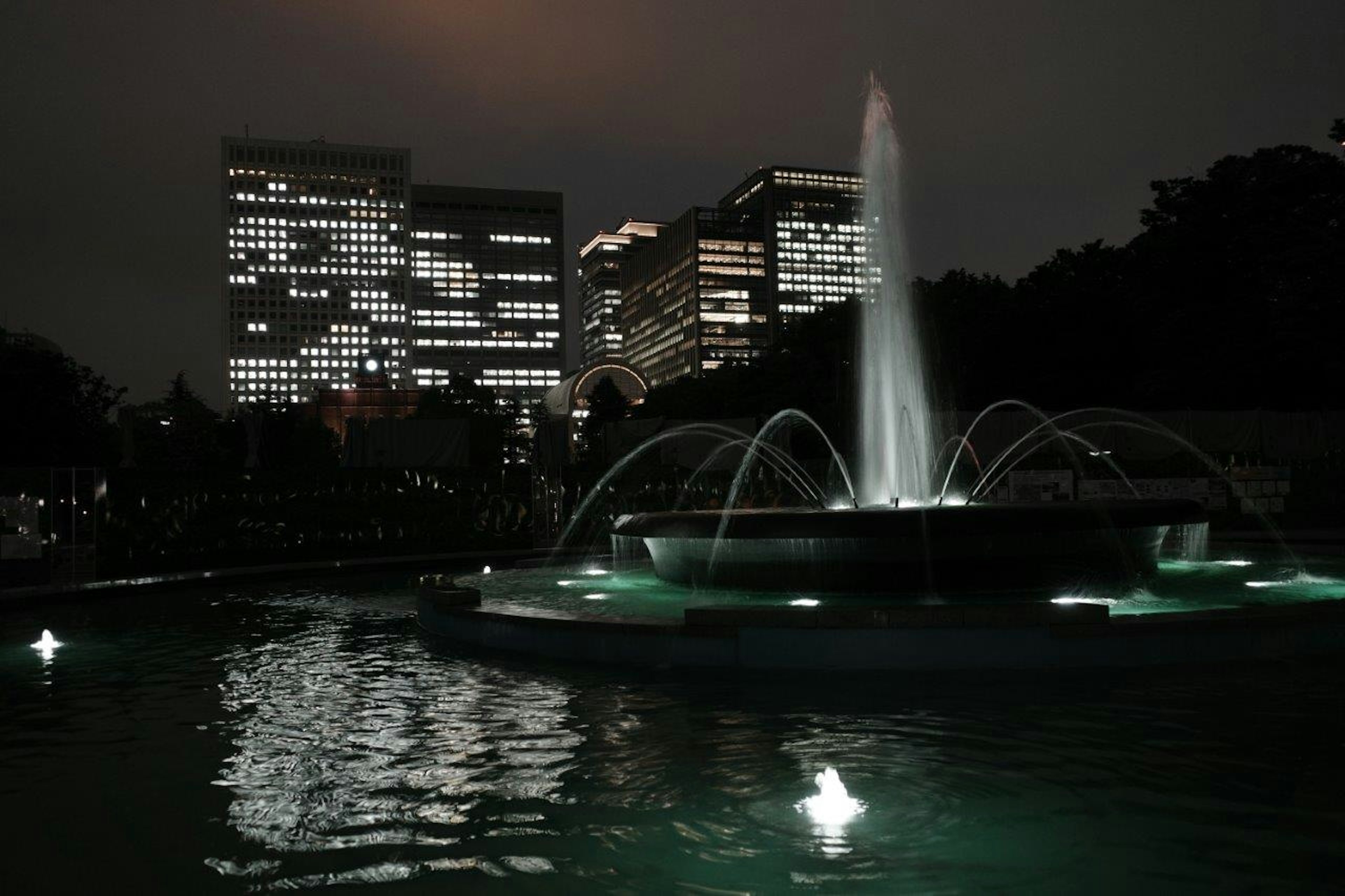 夜間照明的噴泉與城市建築在水中的倒影