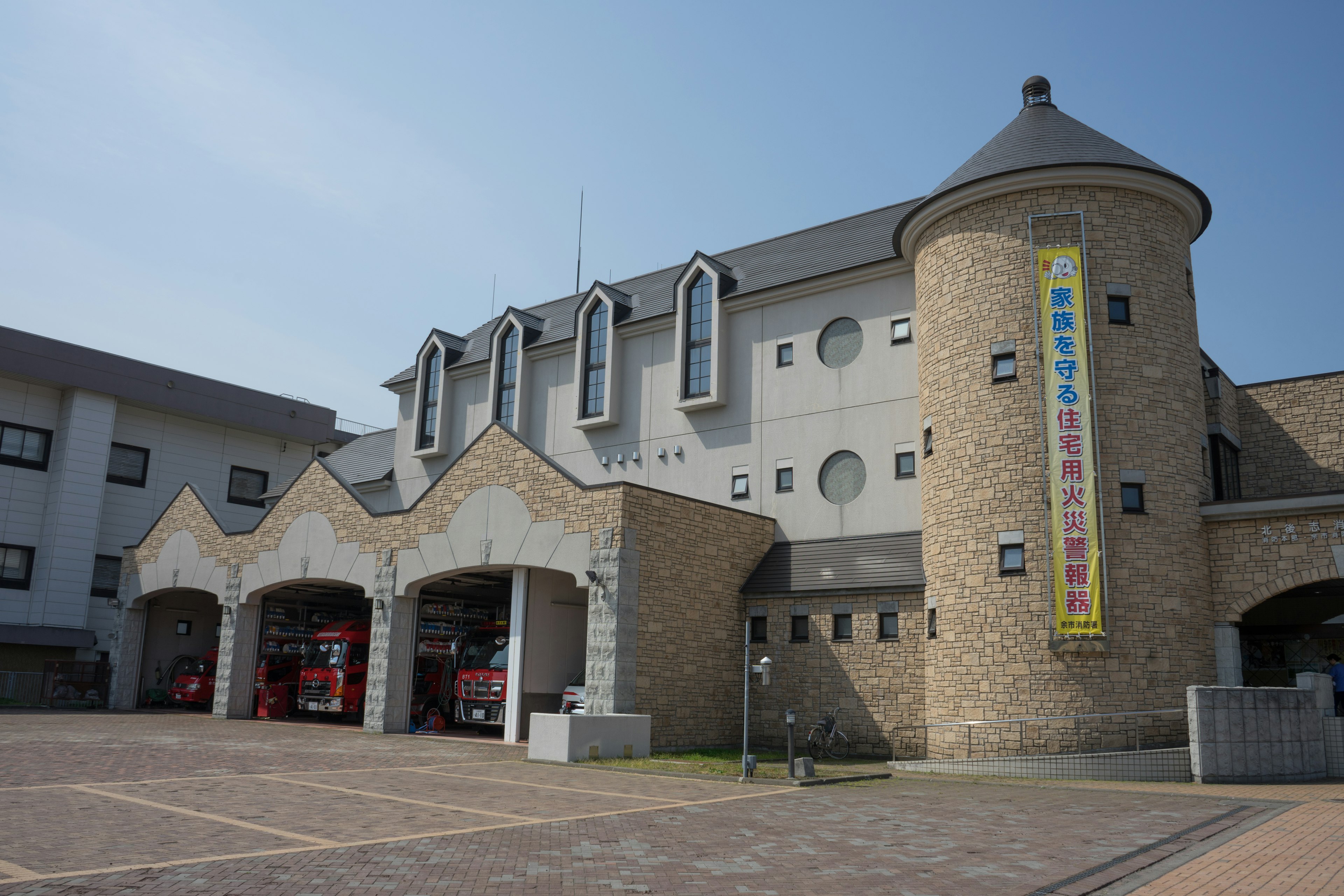 Außenansicht einer Feuerwehr mit Steinturm und modernem Design