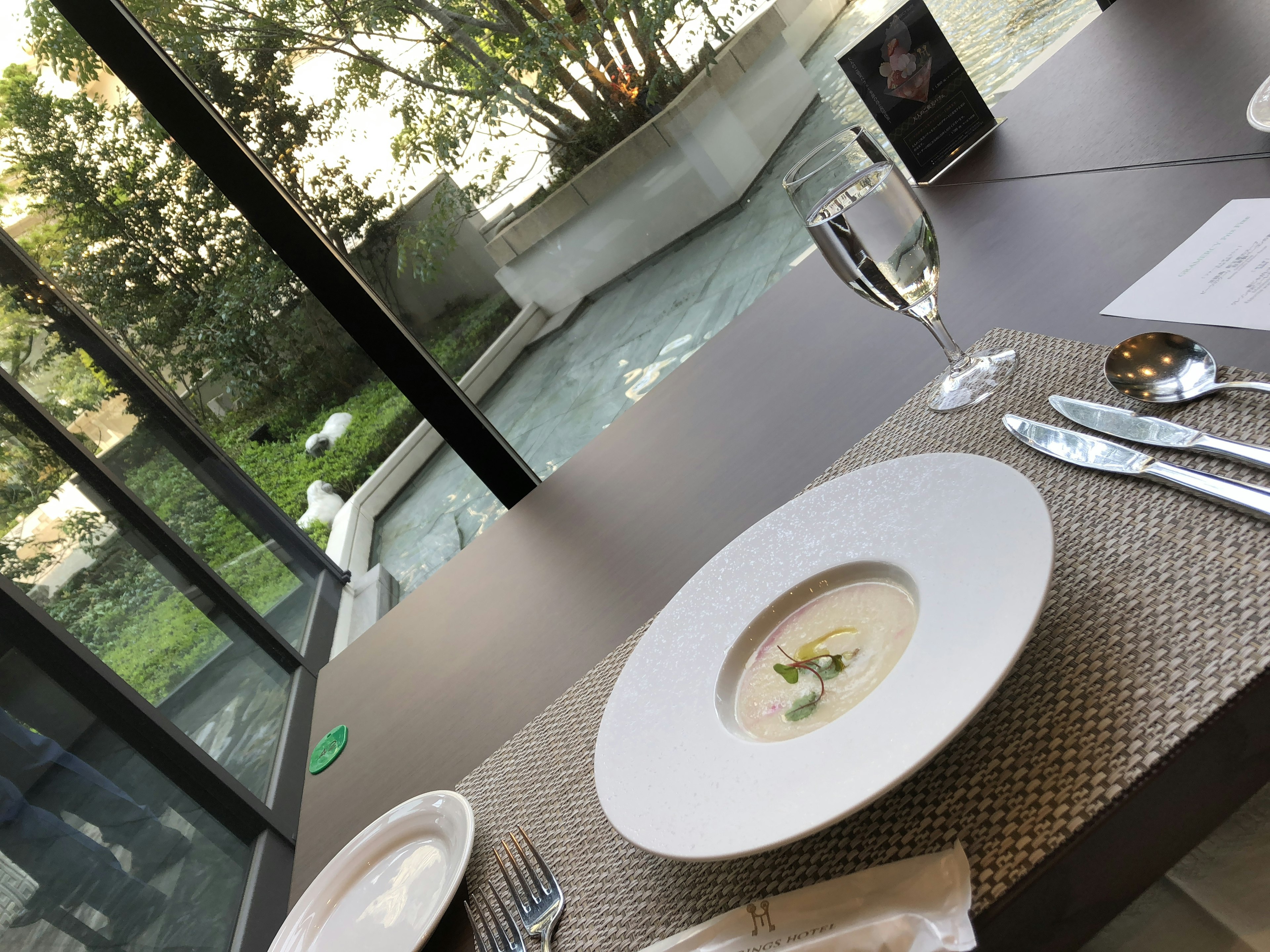 Tisch mit Suppenteller und Glas mit Blick auf einen schönen Garten