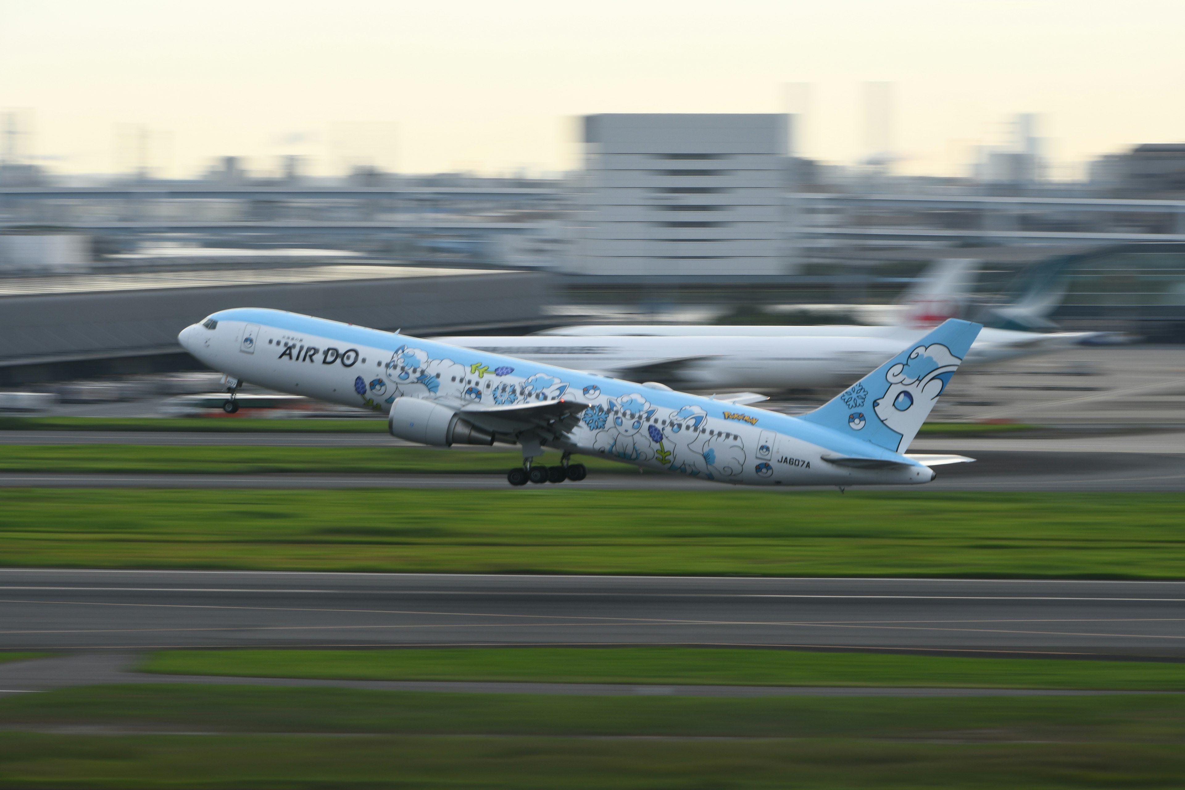 青いデザインの飛行機が滑走路を離陸している