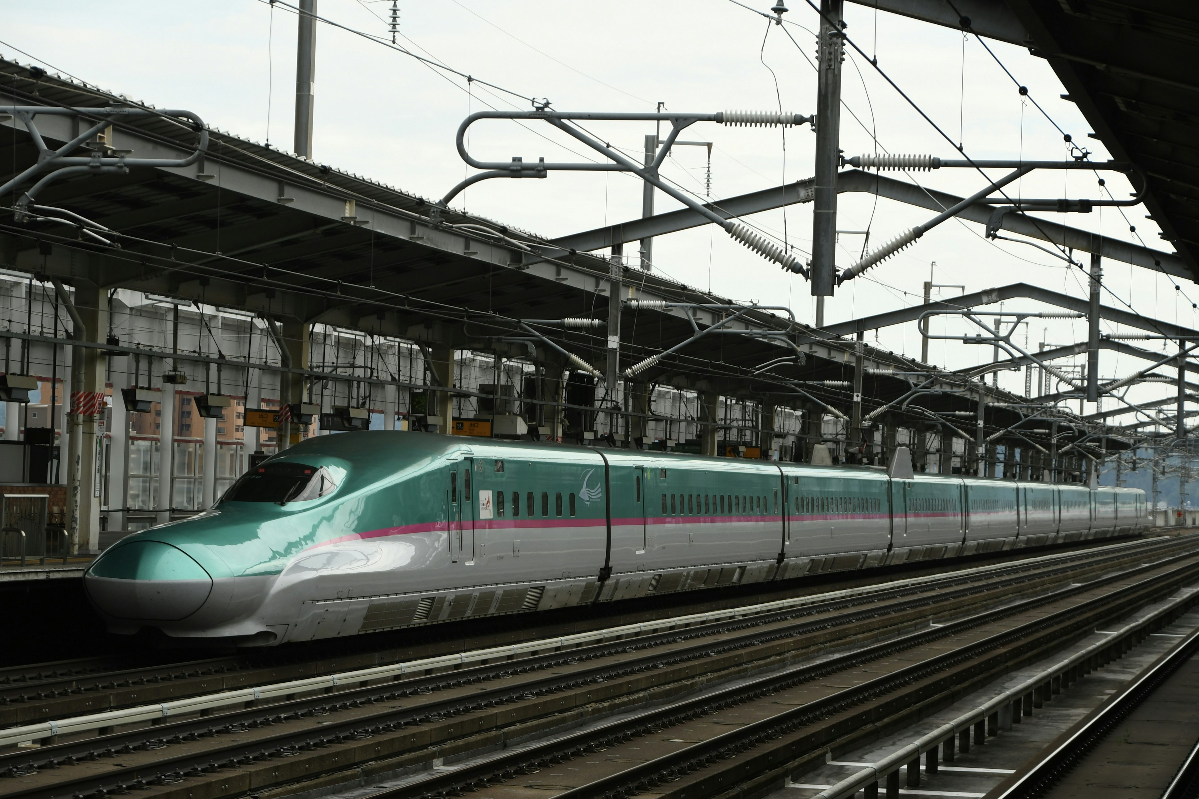 A sleek Shinkansen train at a railway station with modern architecture