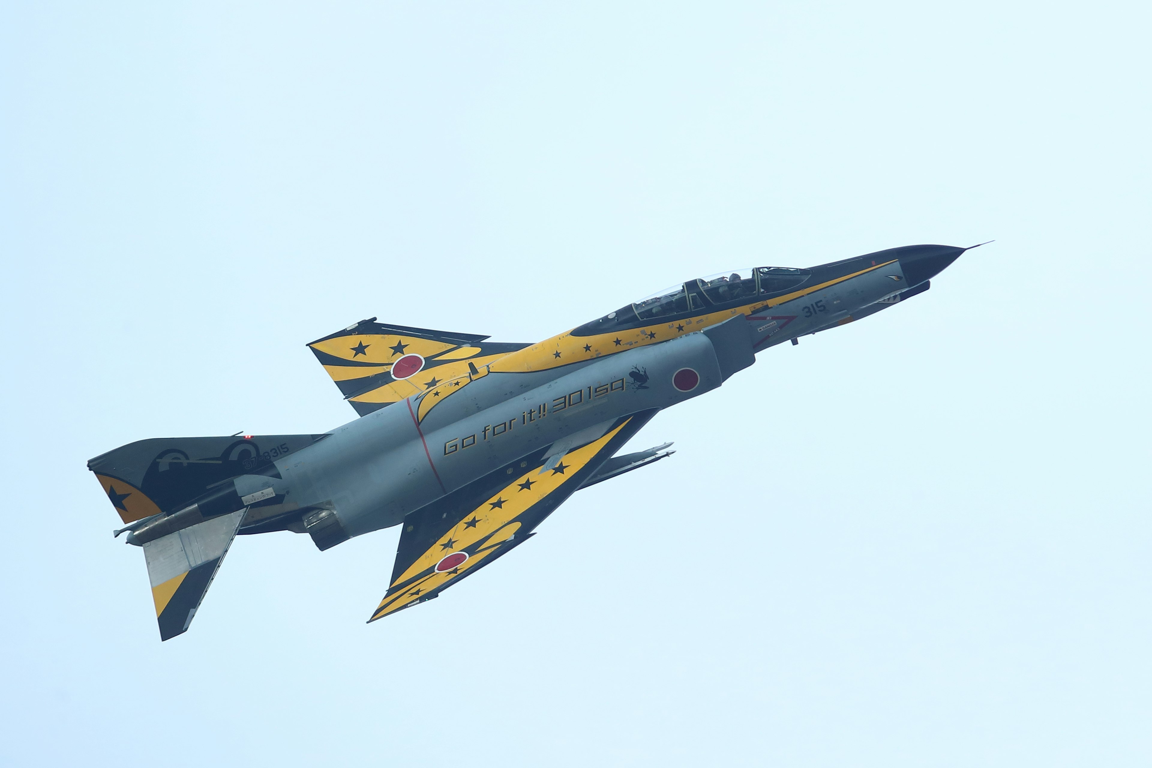 A fighter jet with yellow and black coloring soaring into the sky