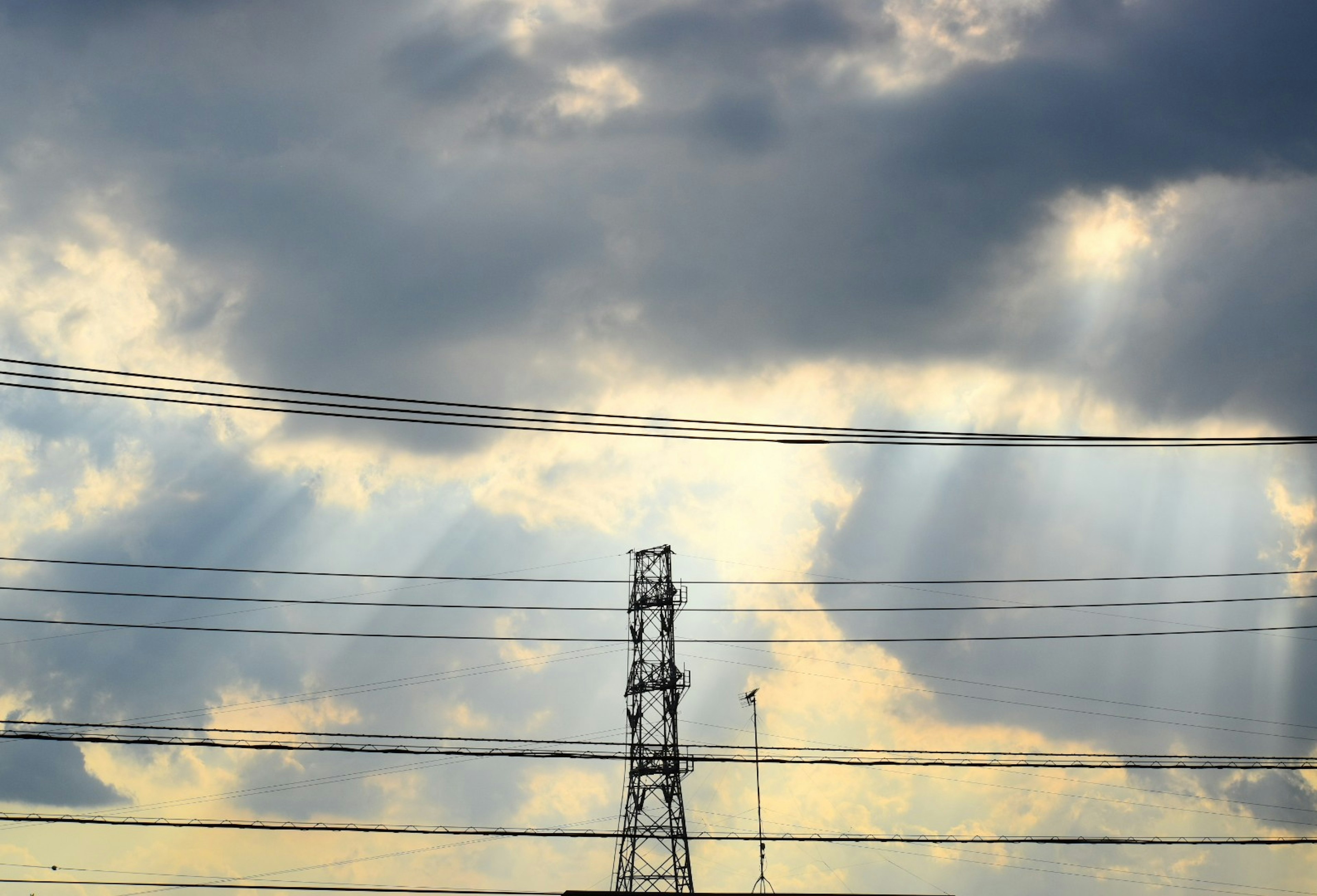 Paesaggio con nuvole e raggi di luce con un palo elettrico